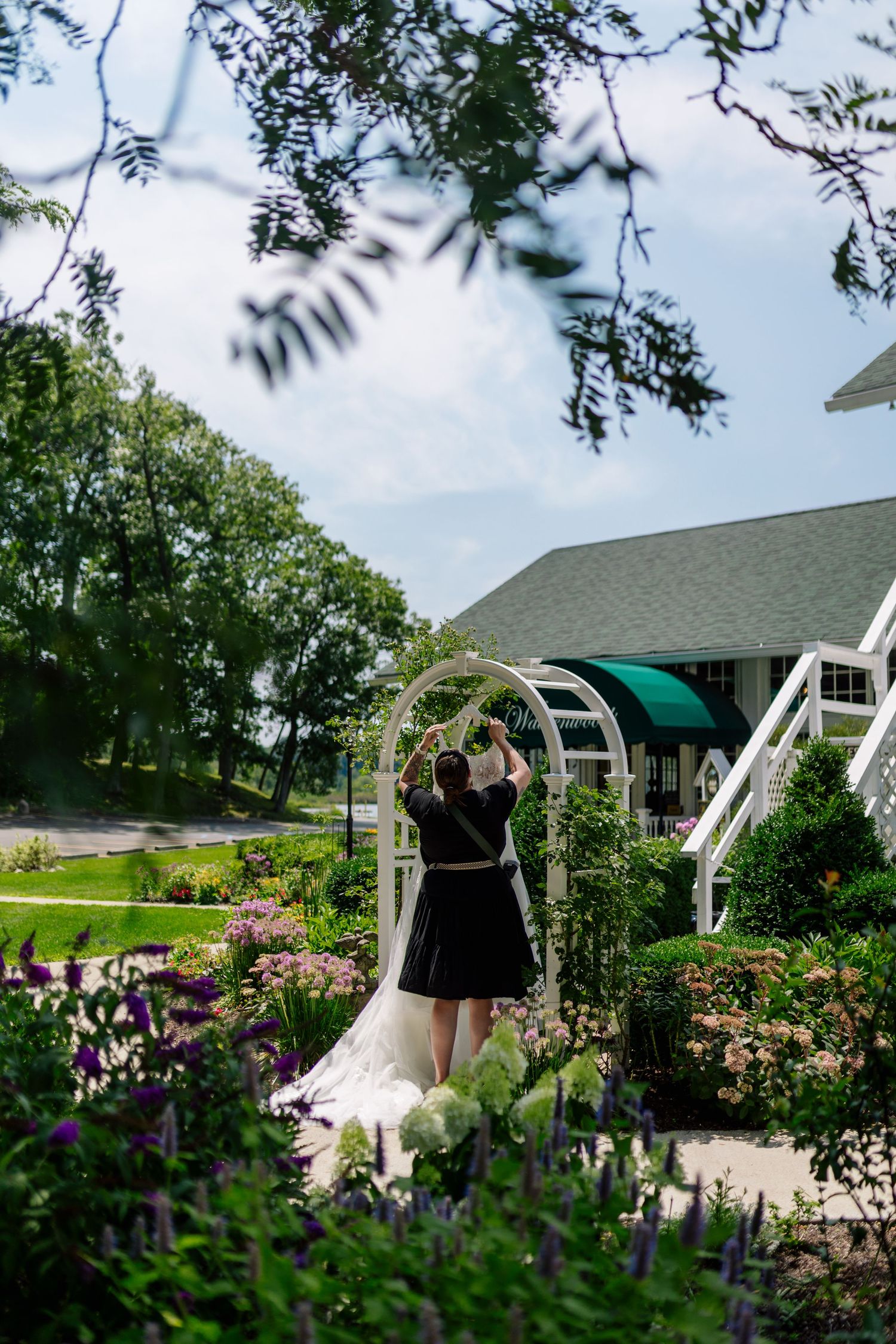 A garden wedding scene with an archway covered in flowers and greenery.