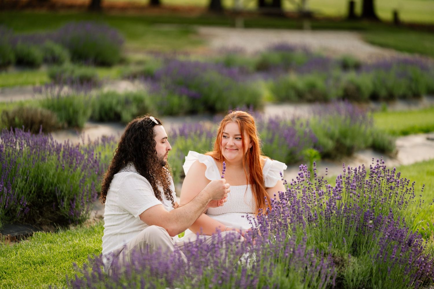 Two people sit among blooming lavender bushes sharing a happy conversation.