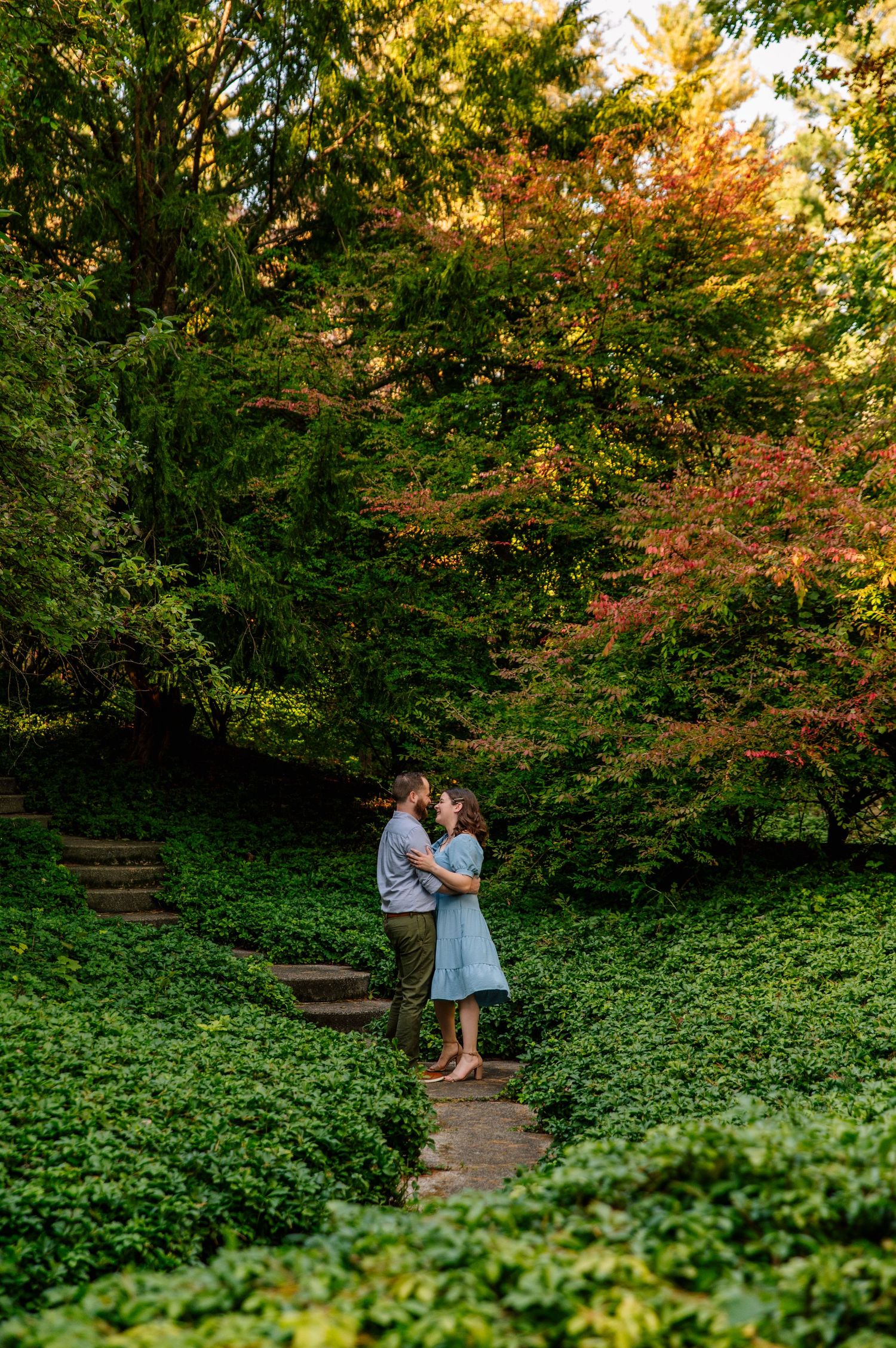 Romantic moment on garden steps surrounded by lush greenery and autumn foliage.