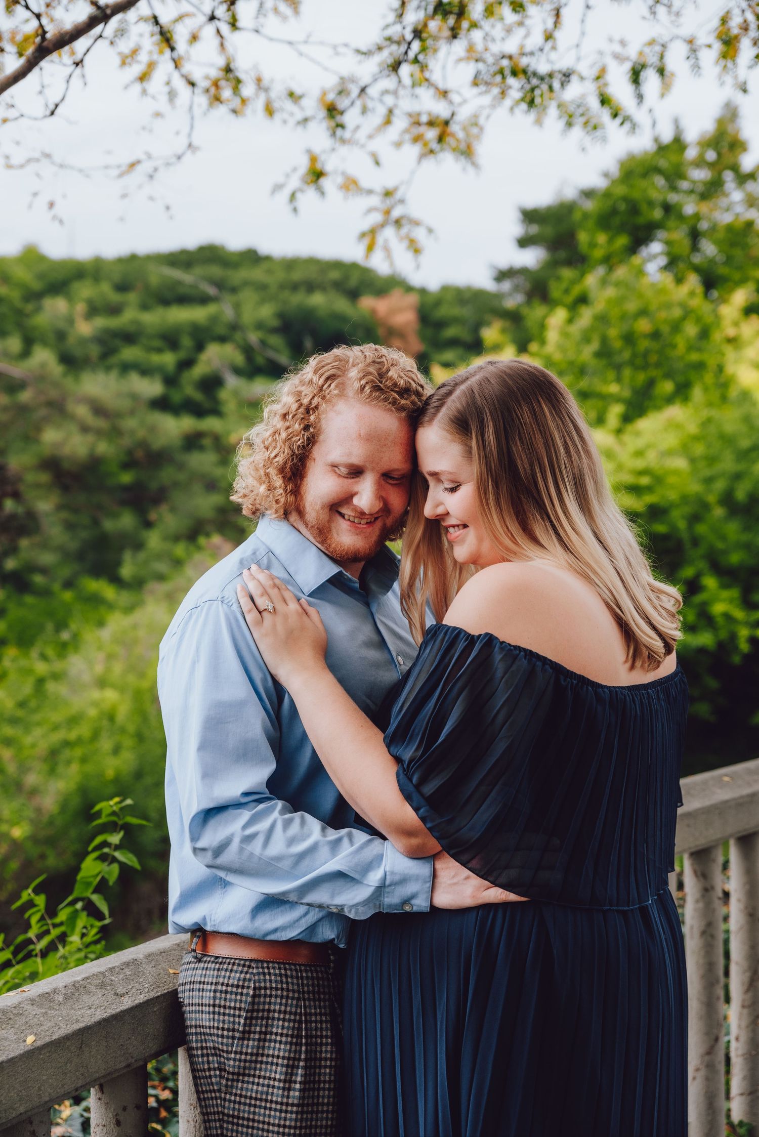 Intimate couple portrait on balcony with lush green background.