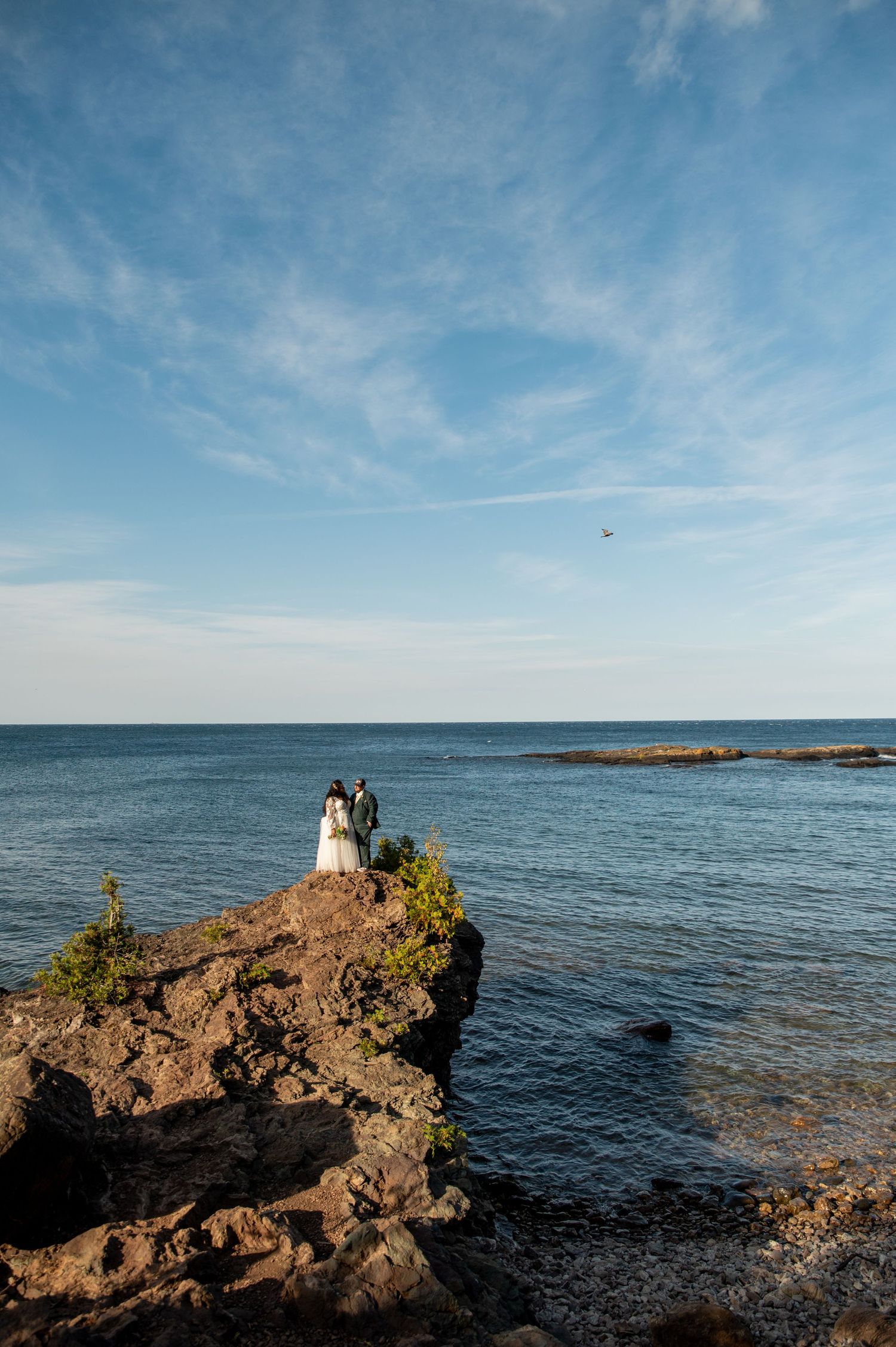 Scenic coastal landscape with rocky outcrops against blue ocean and sky during sunset at the shoreline.