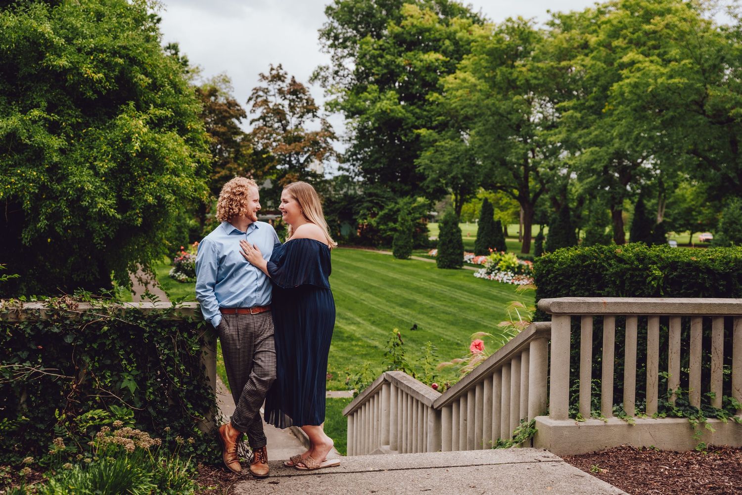 Couple standing on garden steps surrounded by trees and landscaping.