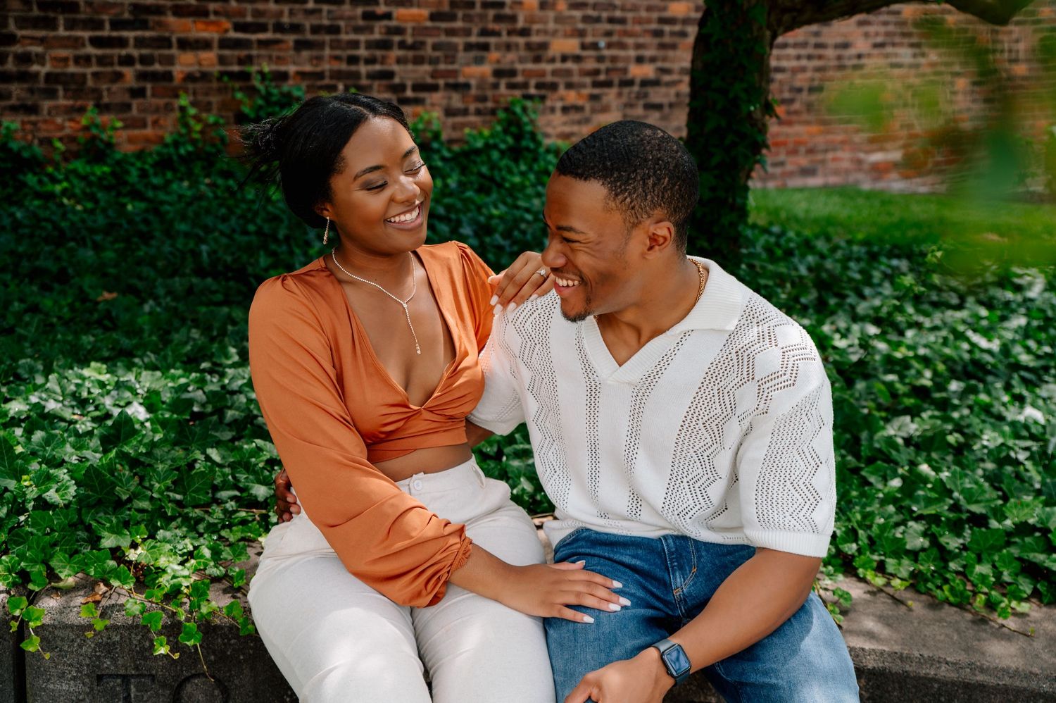 Couple sharing playful moment while sitting outdoors in casual attire.