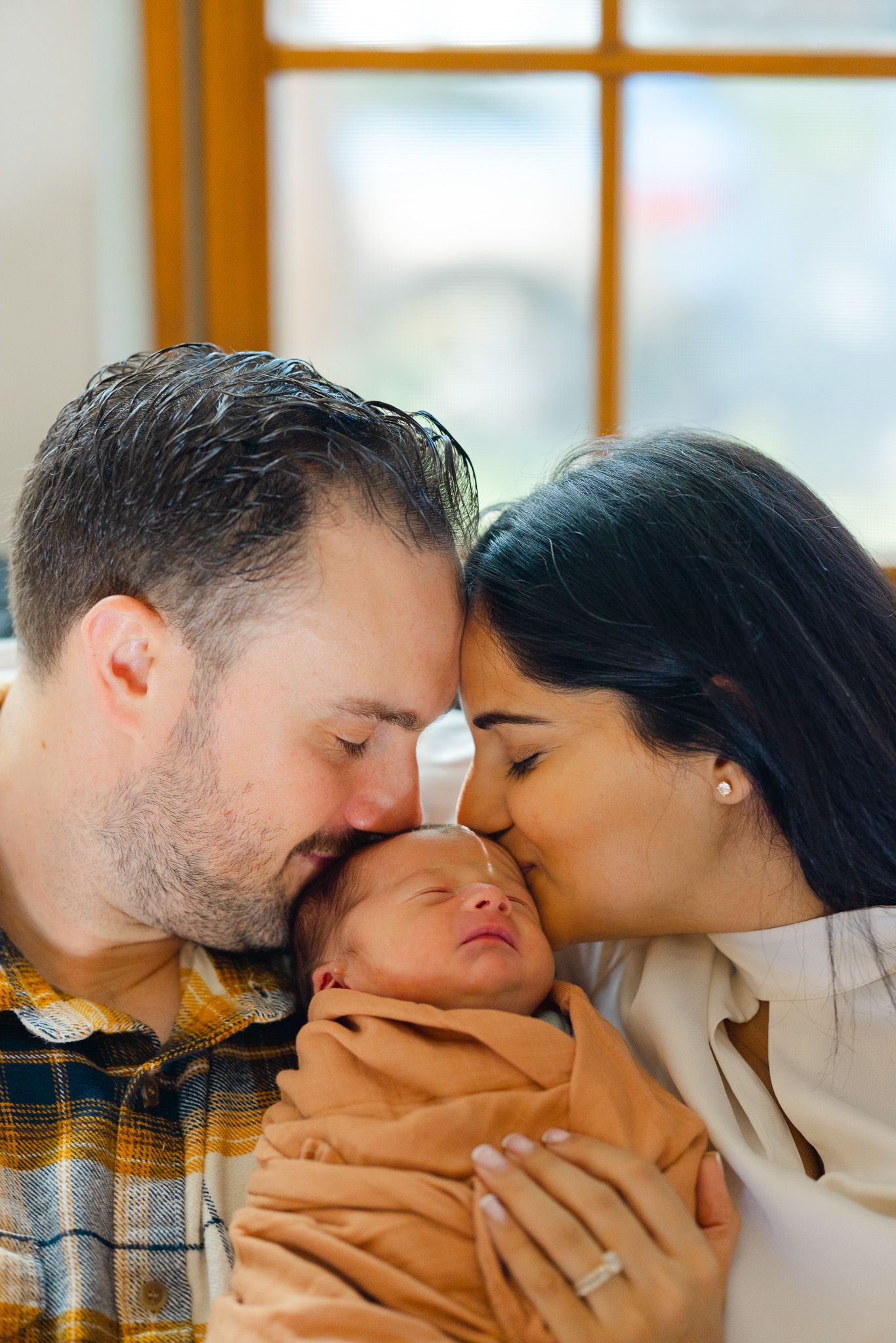 A series of four photos showing tender family moments as parents kiss their baby's cheeks.