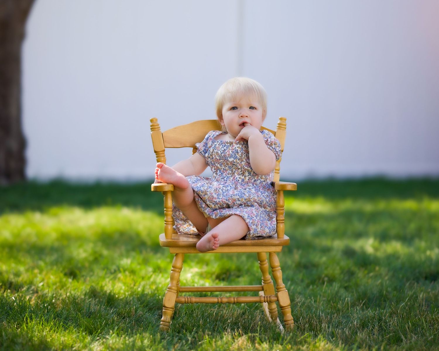 A wooden rocking chair sits on lush green grass in a backyard on a sunny day with multiple views of the same scene.