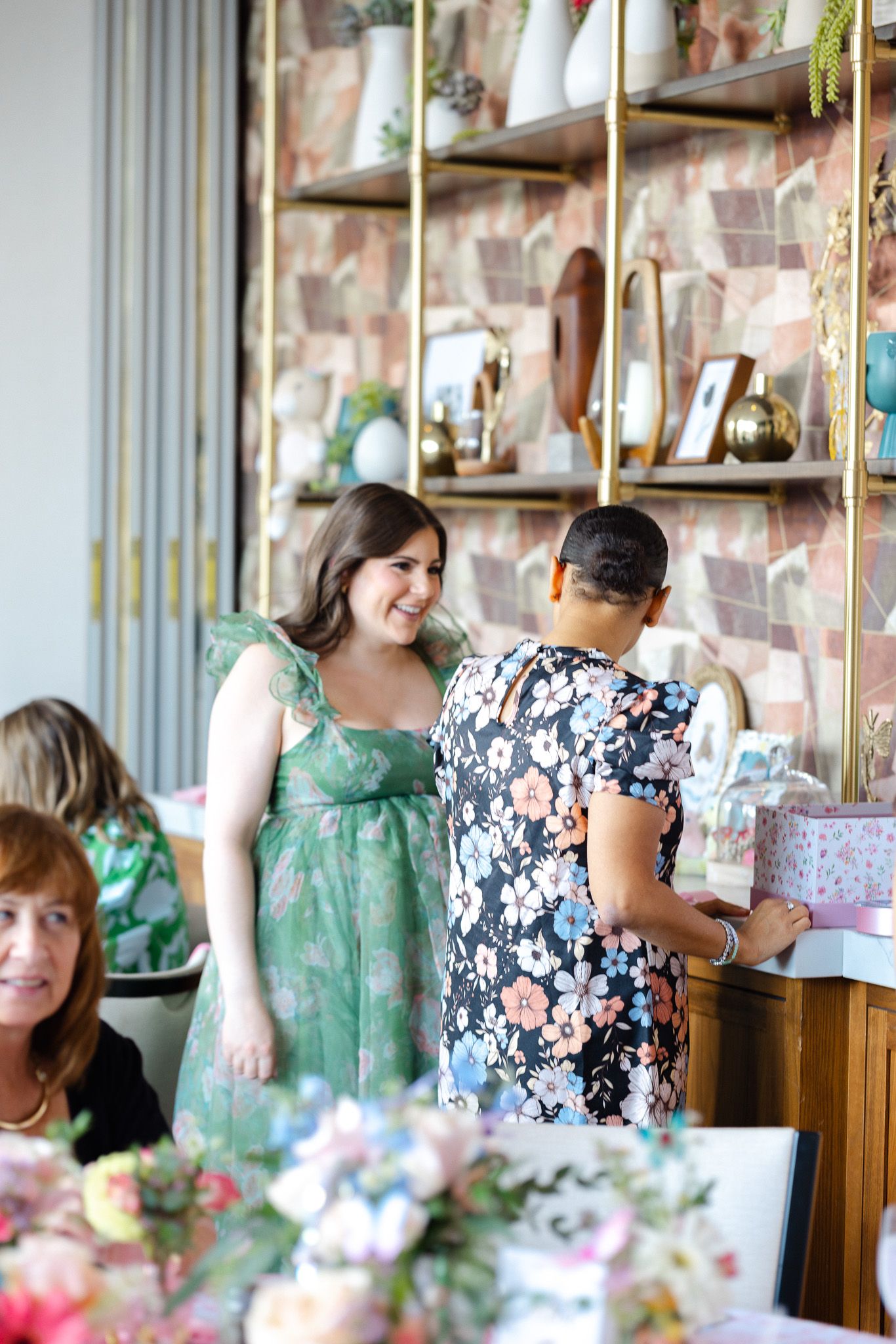People browse items at a charming retail shop with floral decorations and shelving displaying various gifts and decor.