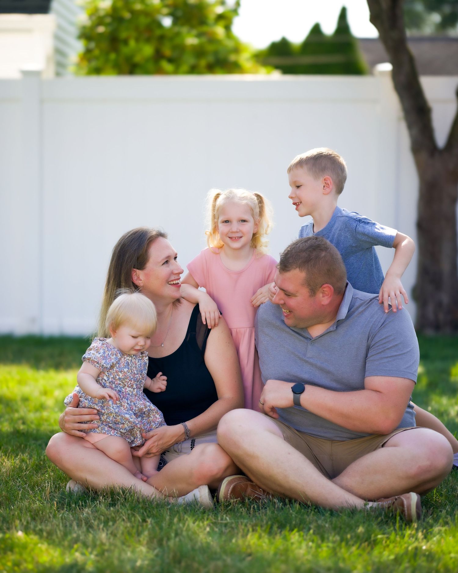 A family relaxes together on green grass during a summer evening outdoor photoshoot.