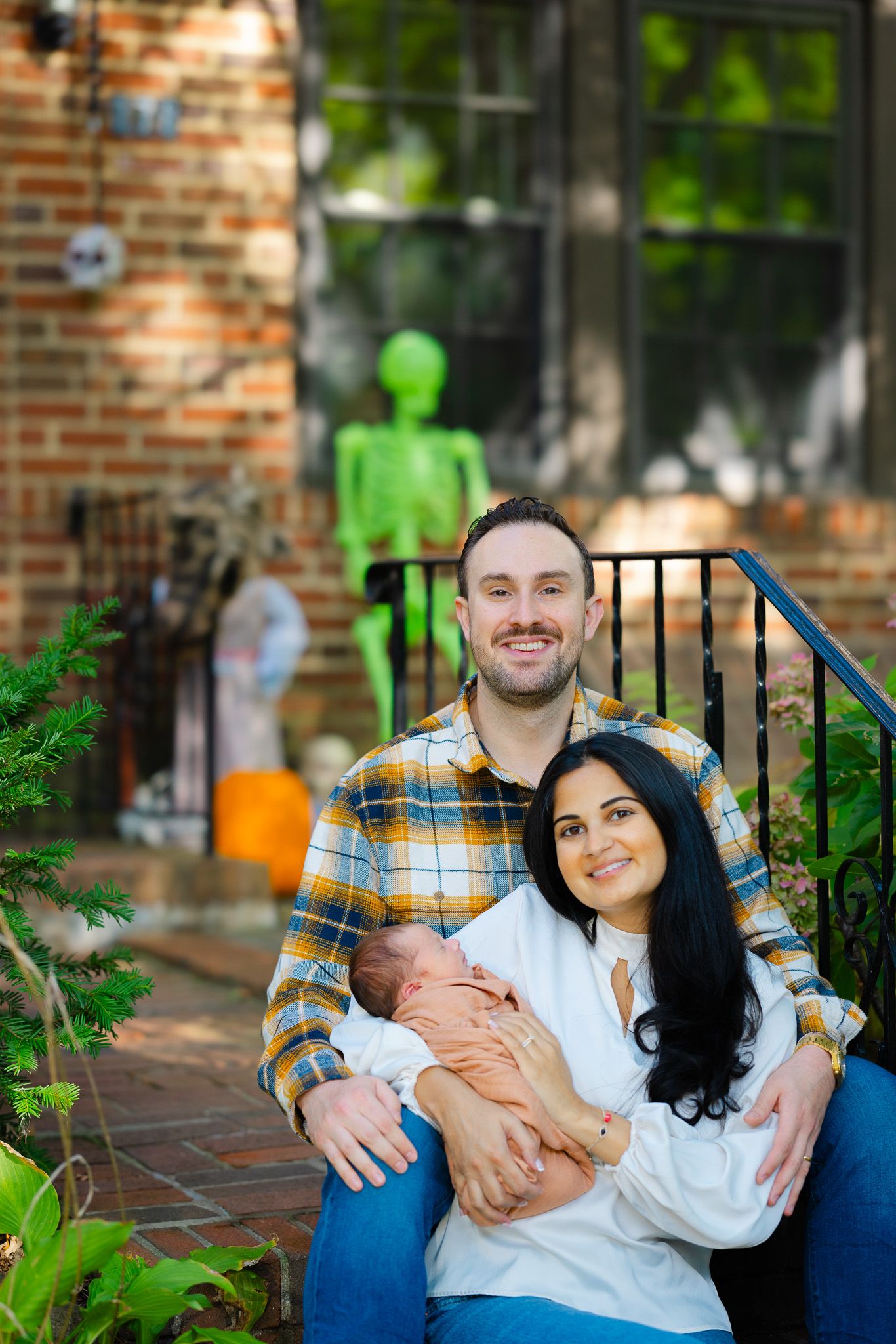 Outdoor family photo session on a brick patio with greenery and blue decor.