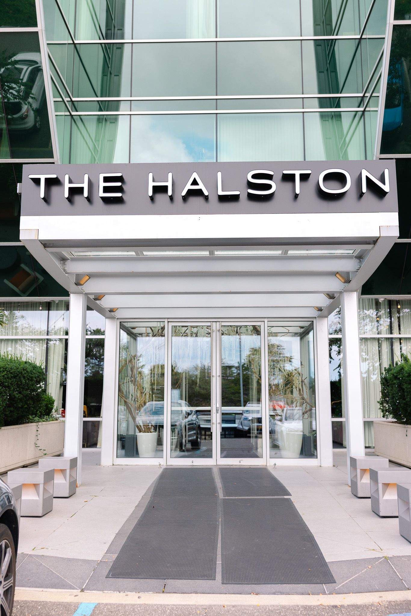 Modern entrance to The Halston building with glass doors and white exterior signage.