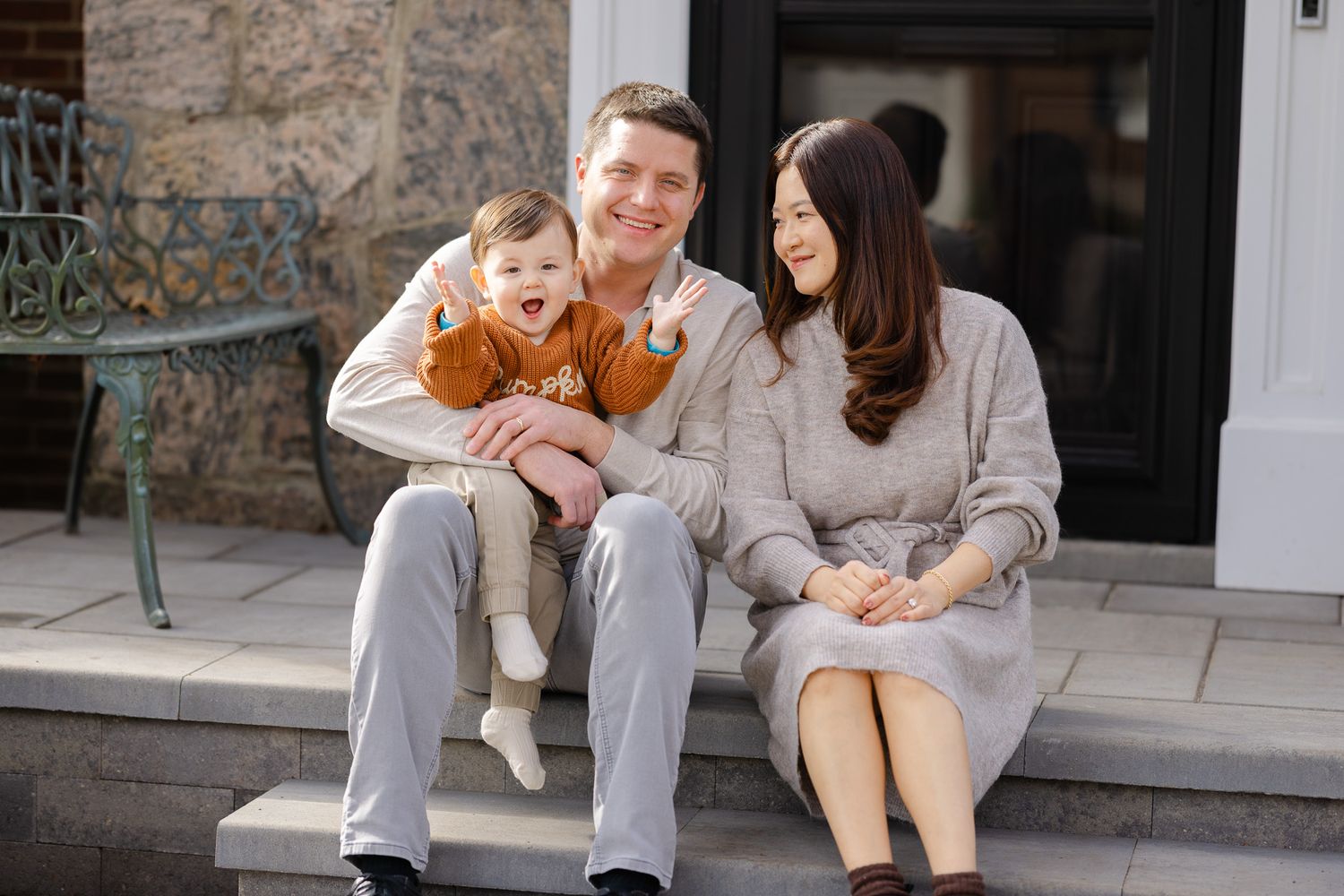 Family sitting on outdoor steps sharing joyful moments together during a casual photo session.