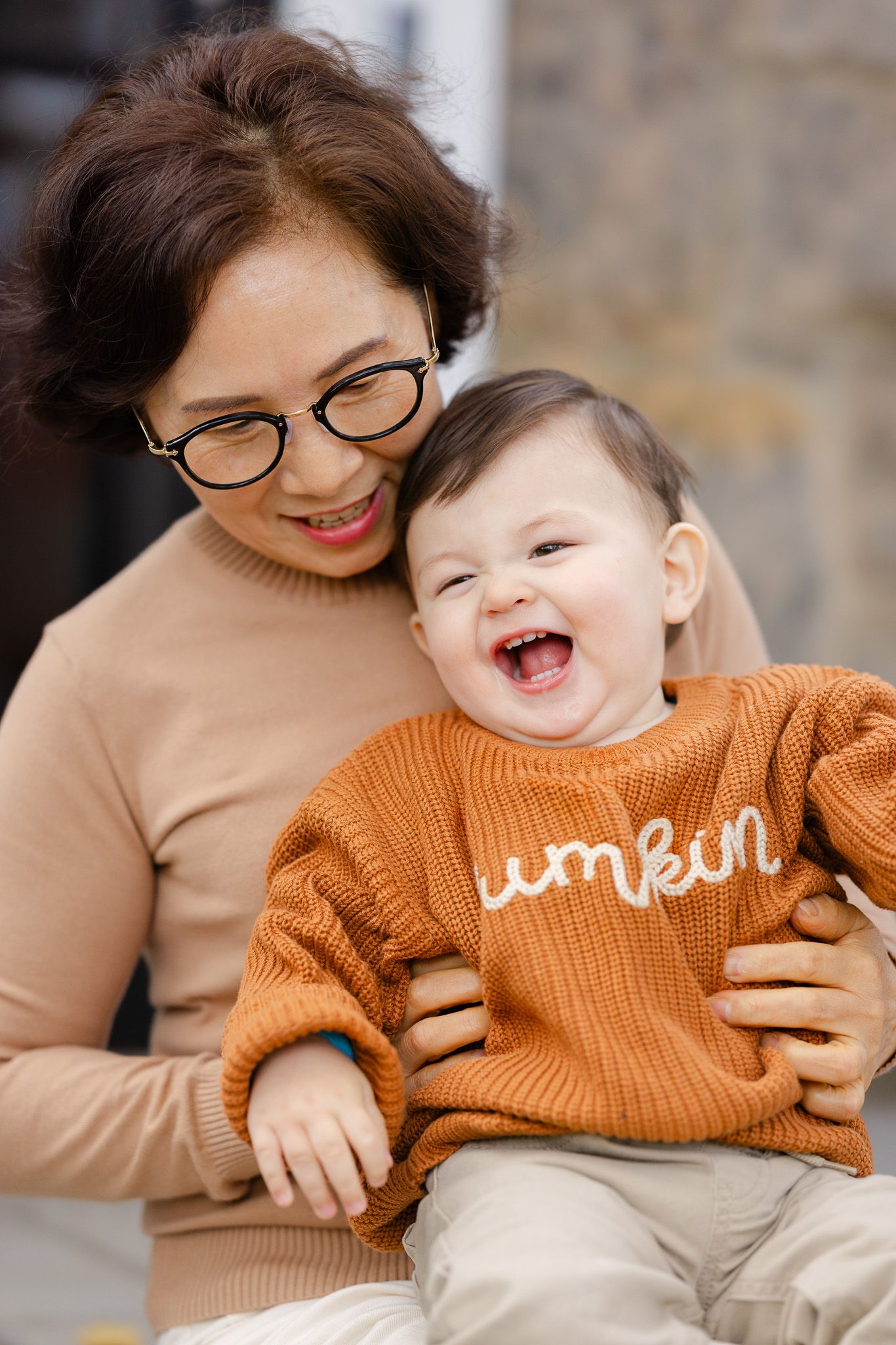 A joyful moment captured showing genuine laughter and smiles while wearing cozy sweaters in warm earth tones.