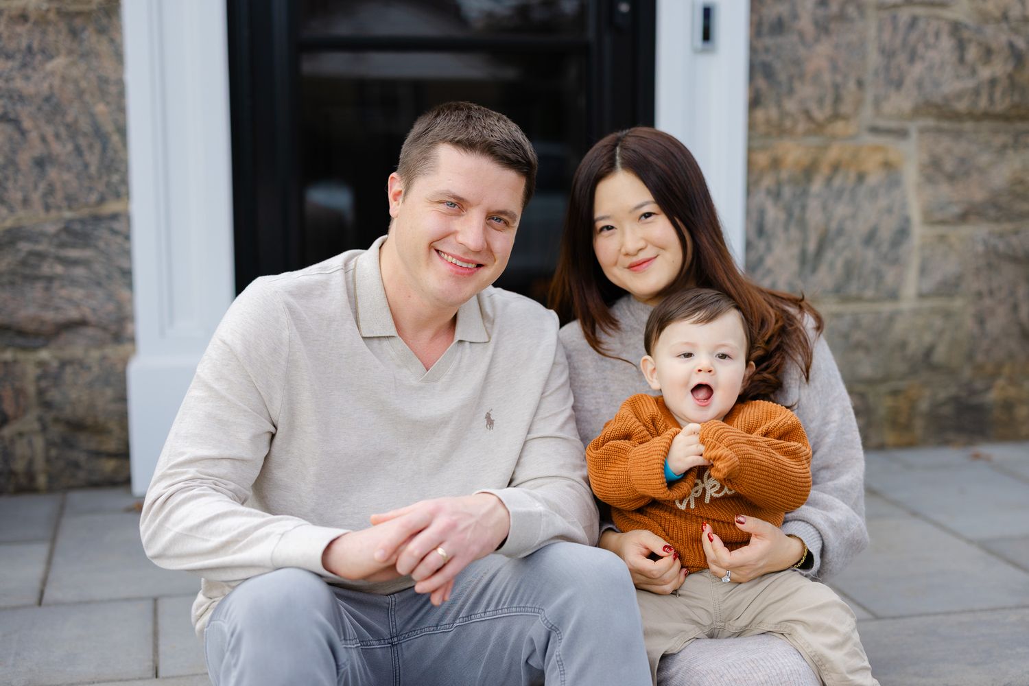 Family sitting together on stone steps outdoors during a portrait session.