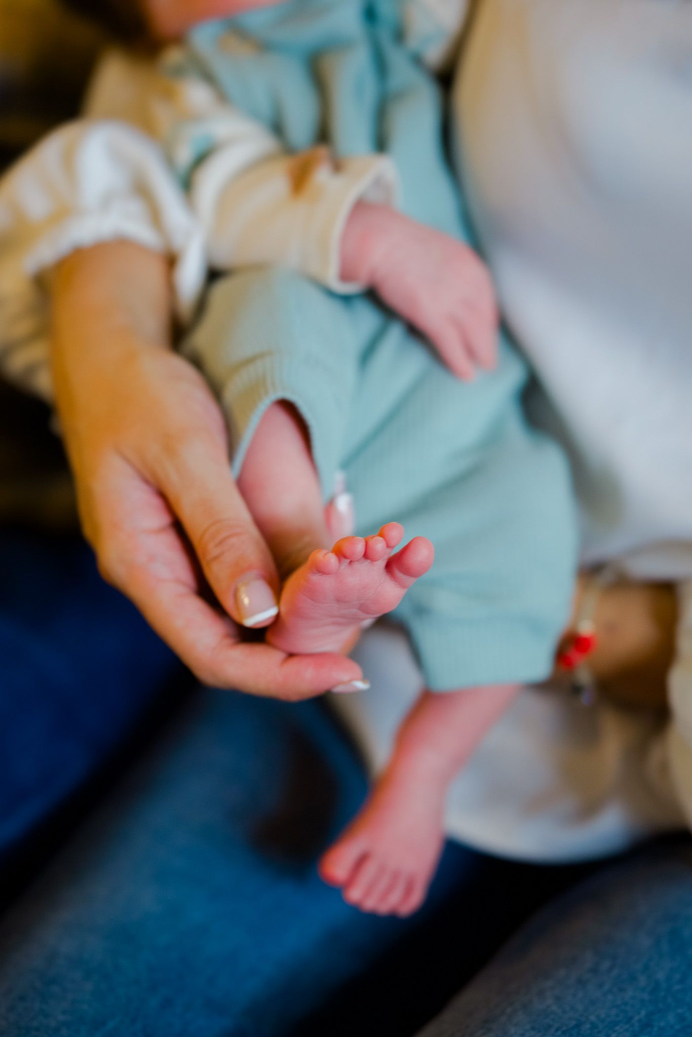 A series of close-up shots showing tiny baby feet being gently held in adult hands against a blue background.