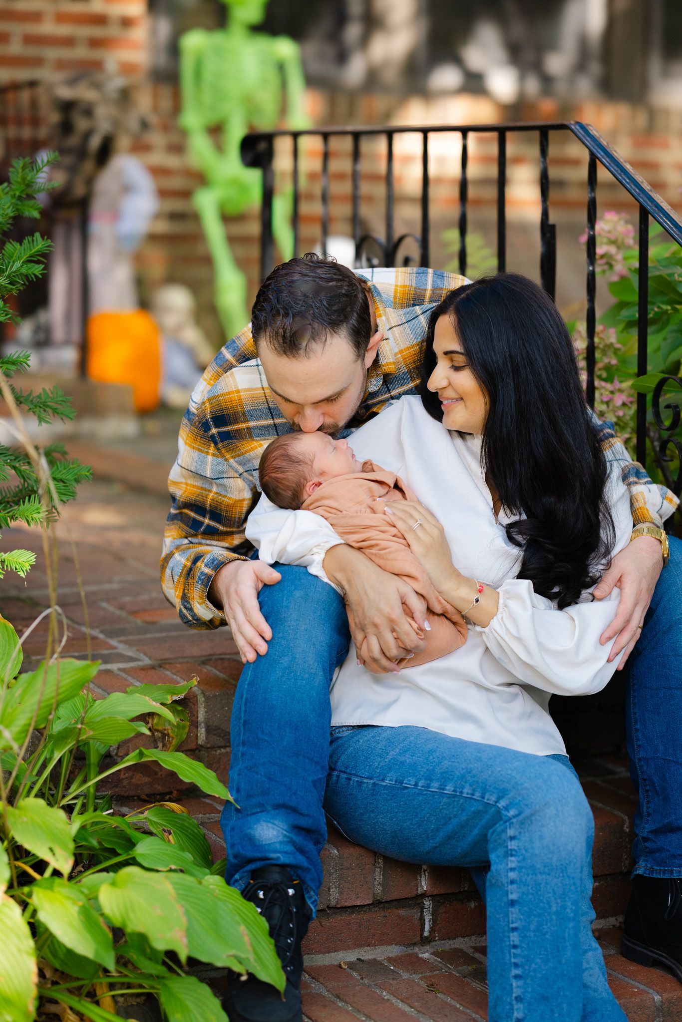 A couple sits together on a bench with greenery in the background sharing an intimate moment.