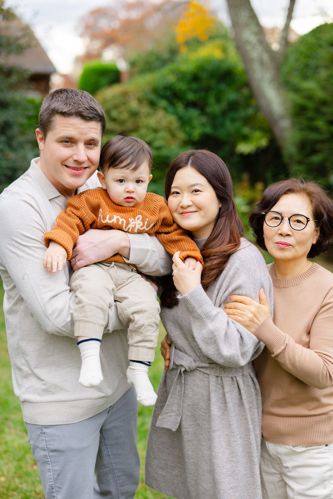 A family wearing coordinated gray and beige outfits poses together playfully outdoors in a series of candid shots.
