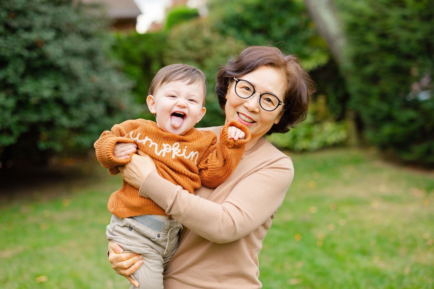 A heartwarming playtime moment in a garden setting with a baby wearing an orange sweater.
