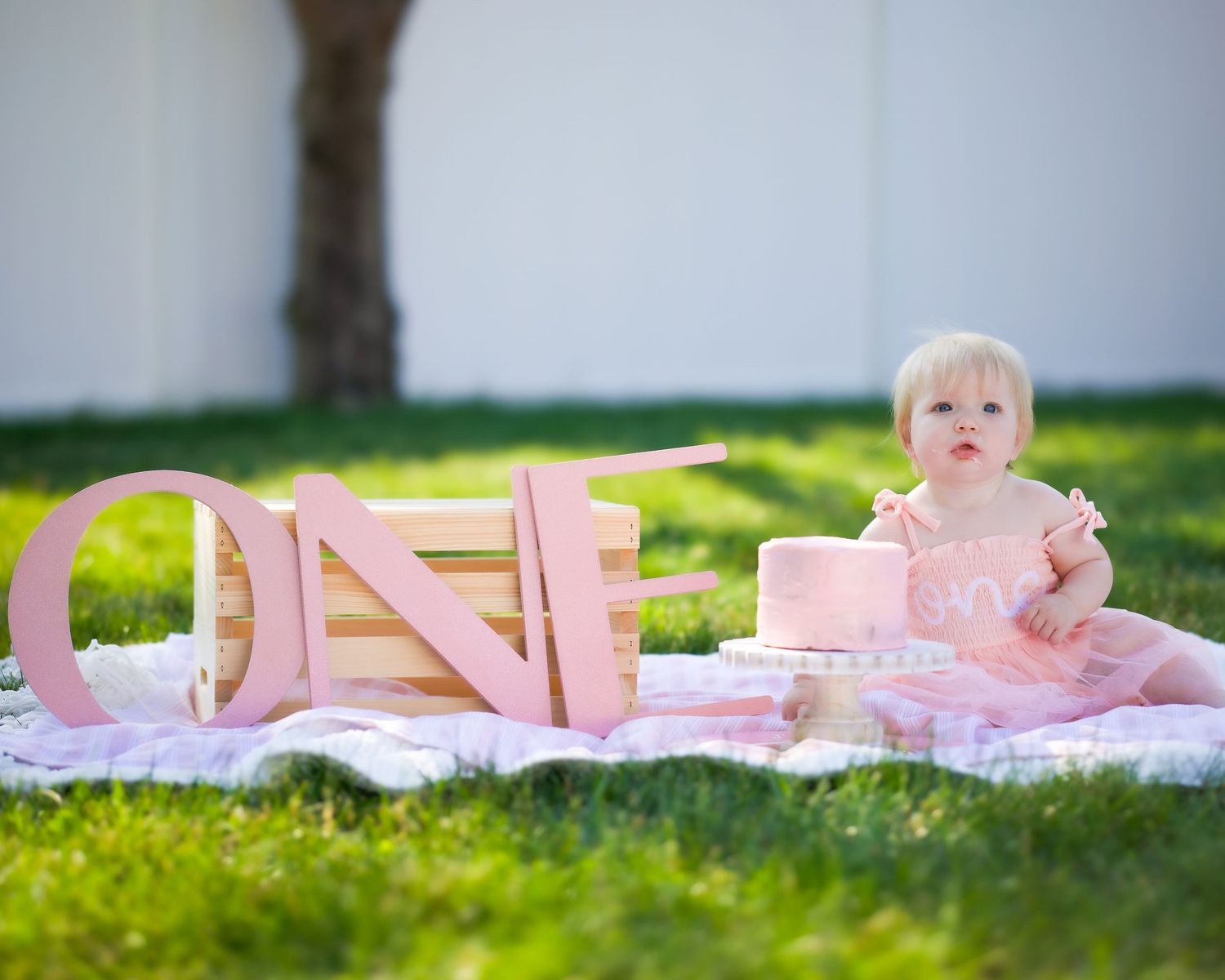 Pink wooden letters spelling out 'LOVE' arranged on green grass in a garden setting.