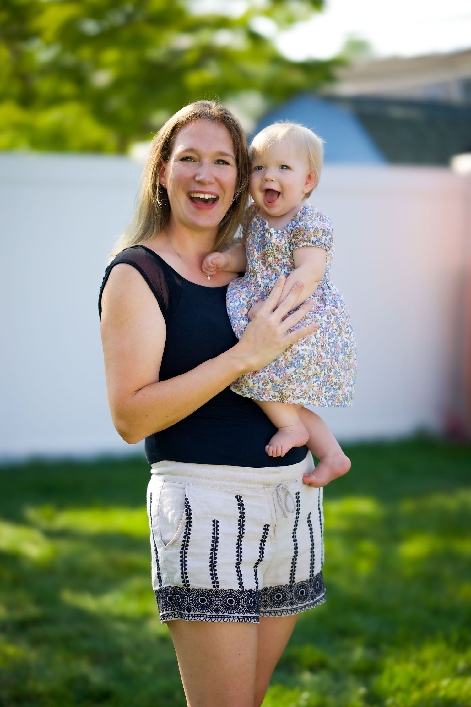 A joyful moment captured outdoors in a garden setting on a sunny summer day with natural greenery in the background.