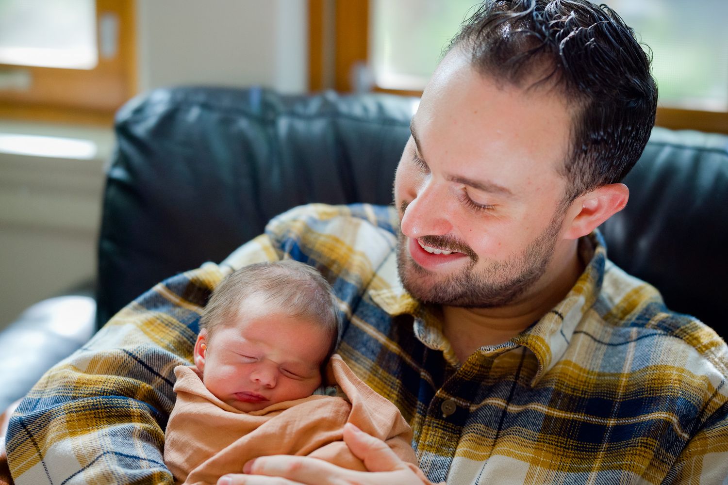 Candid photo series of parents sharing intimate moments with their sleeping newborn in natural light.