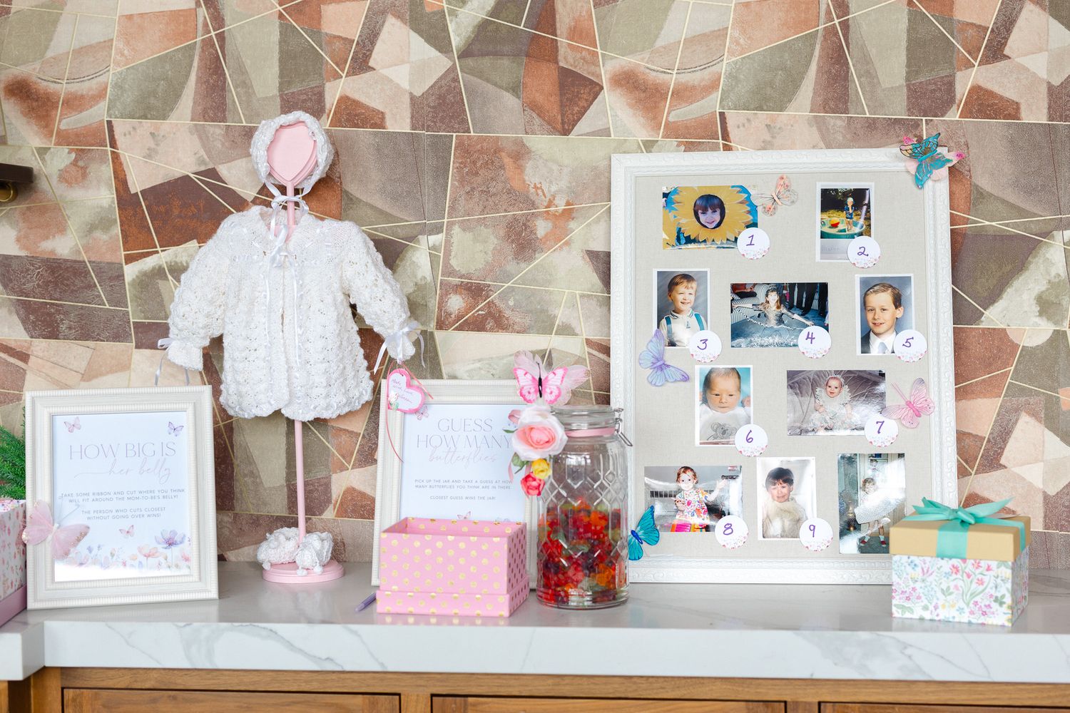 A collection of photos and decorative items displayed on a wall with a pink and neutral color scheme.