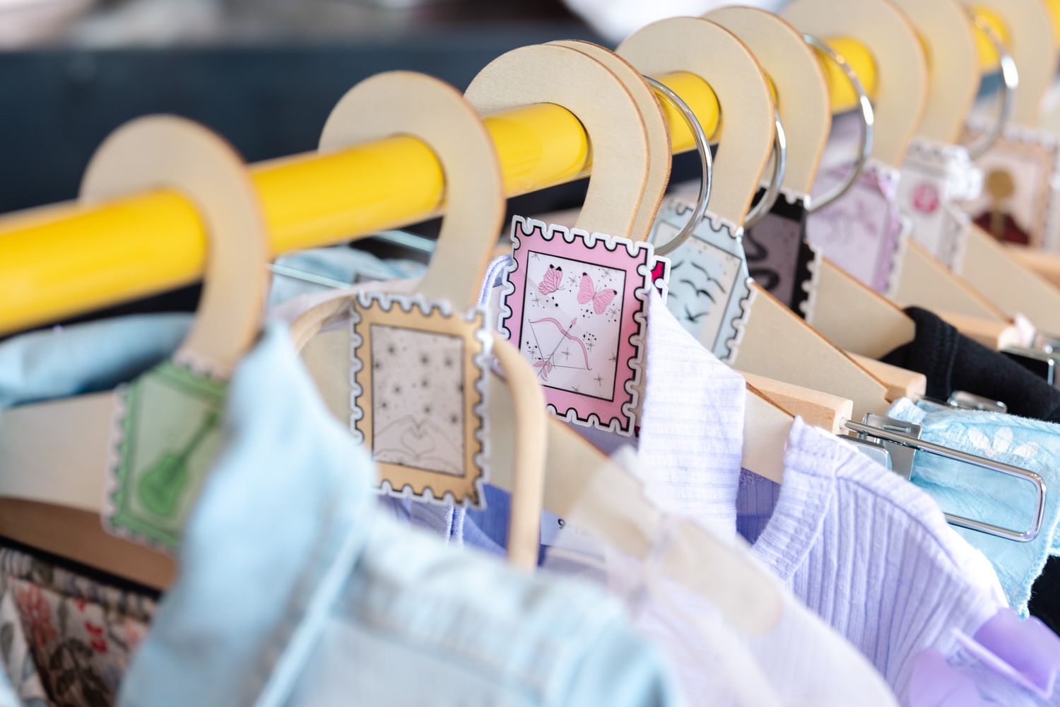 Colorful paper tags with string hang in a row from a display line with soft lighting and blurred background.