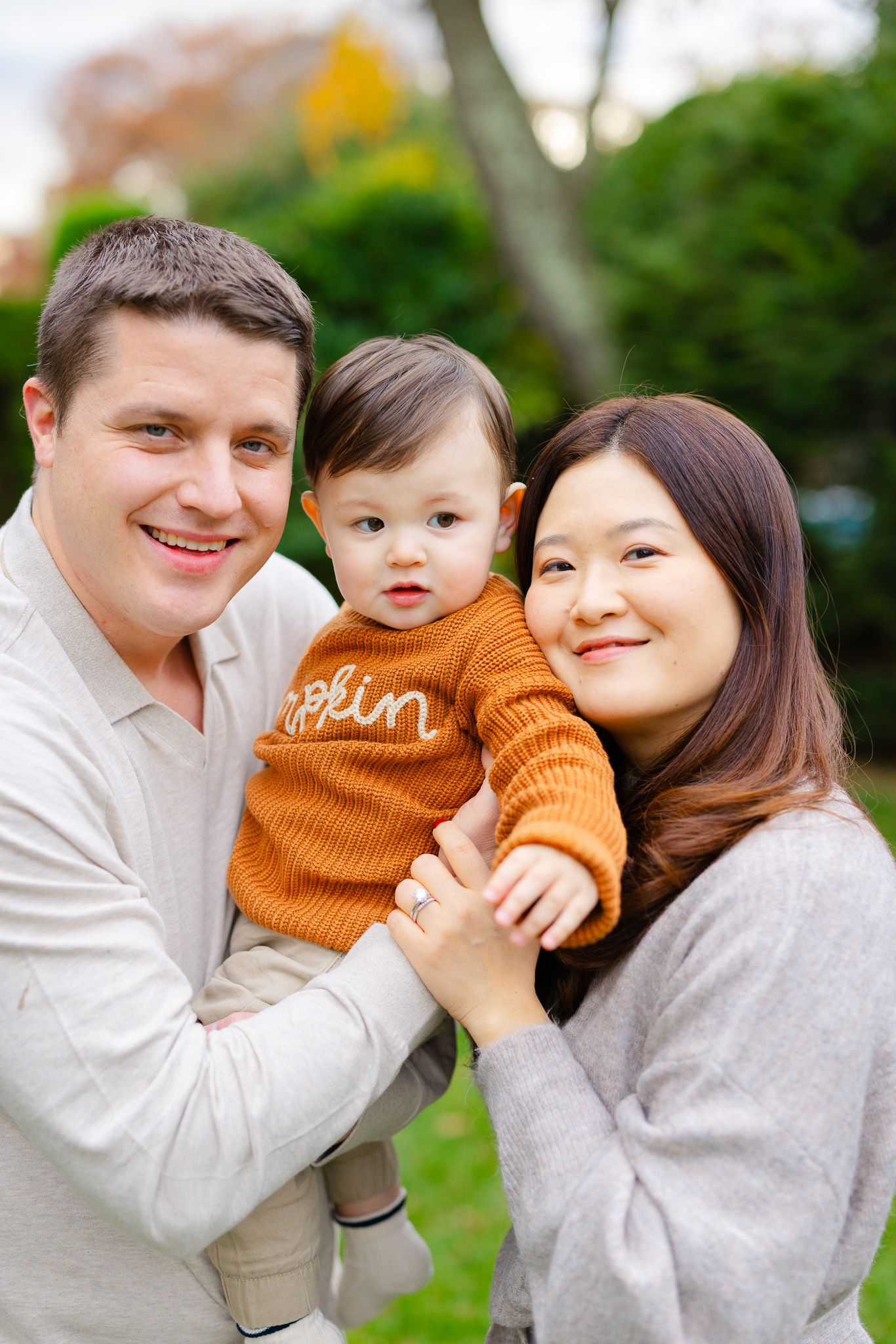 A happy family shares tender moments together in a series of outdoor portrait photos against a green background.