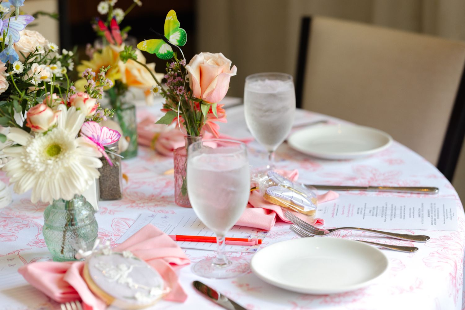Elegant table settings with pink and white floral centerpieces and delicate china plates for a romantic celebration.