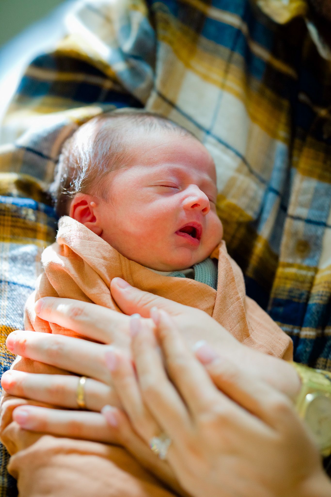 A series of close-up shots showing a newborn baby swaddled in a light colored blanket.