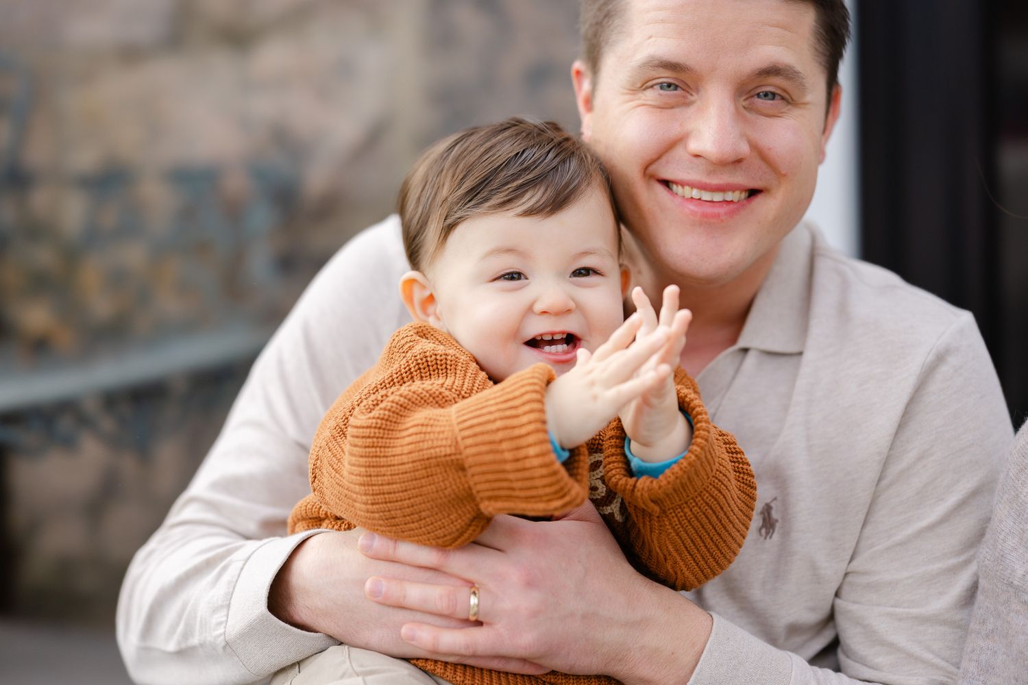 A joyful moment captured in black and white as a child in an orange sweater laughs while being held.