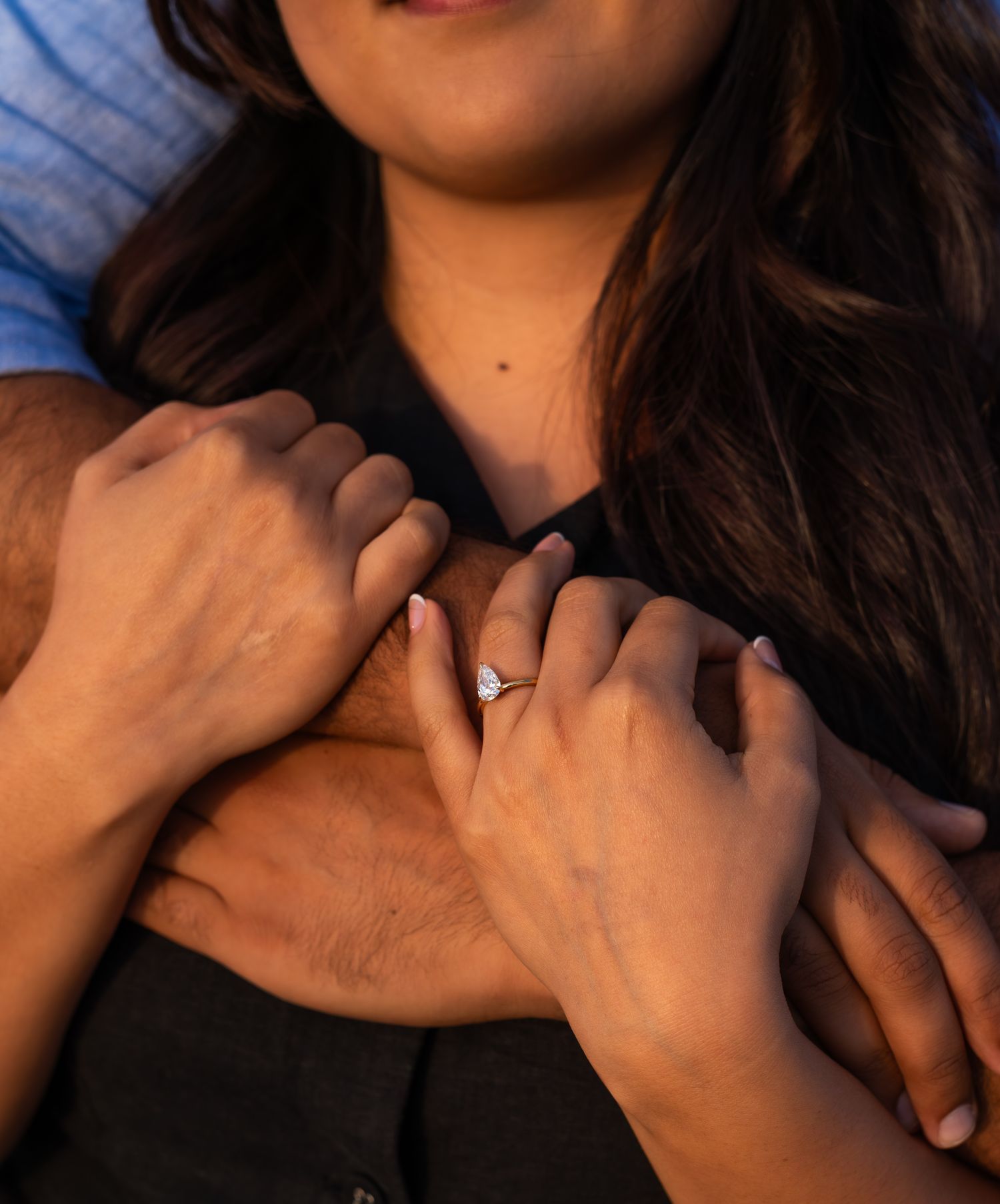 cman hugging woman and her hands are wrapped un his arms with her ring