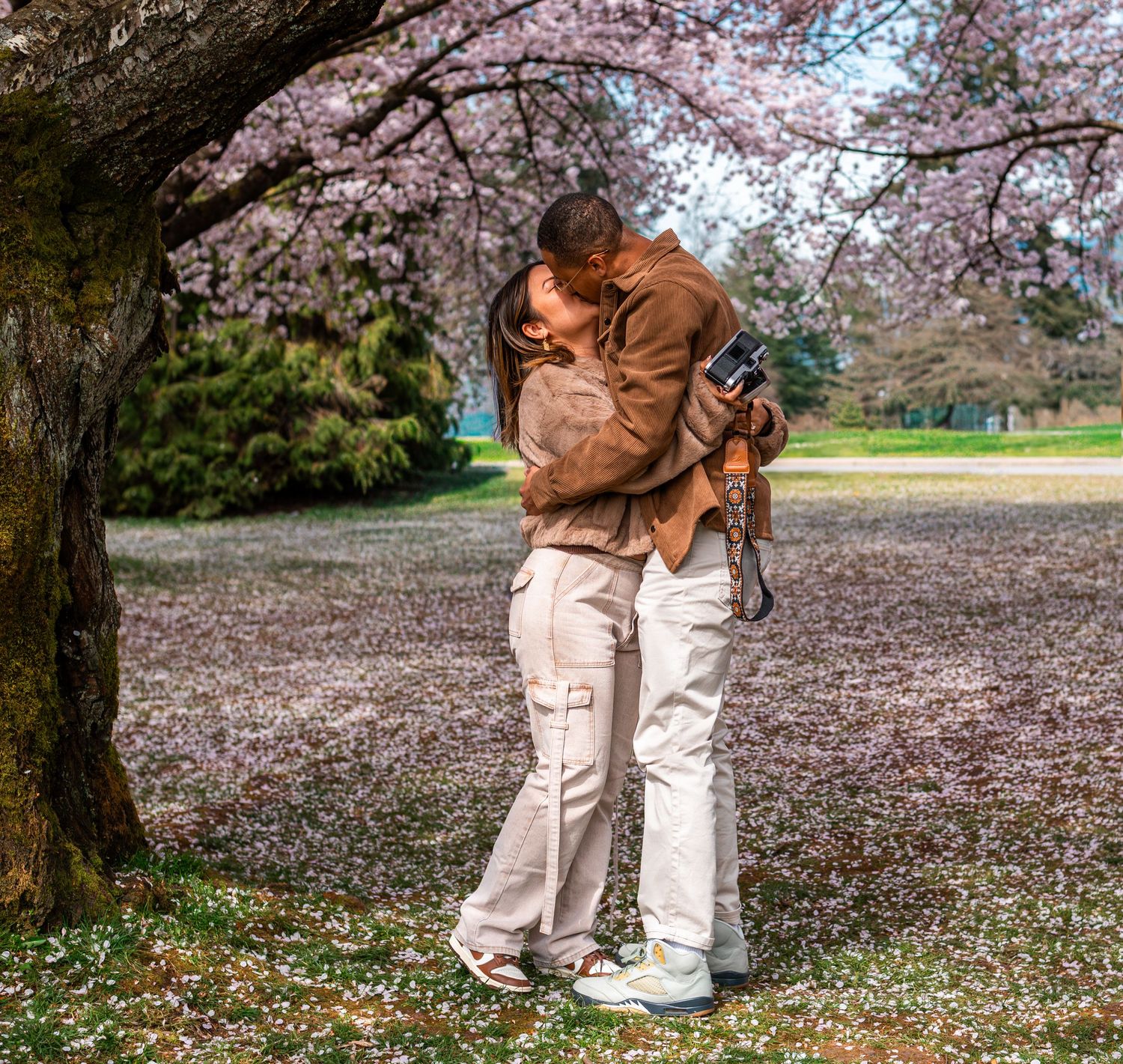 man and woman kissing under cherry blossom trees