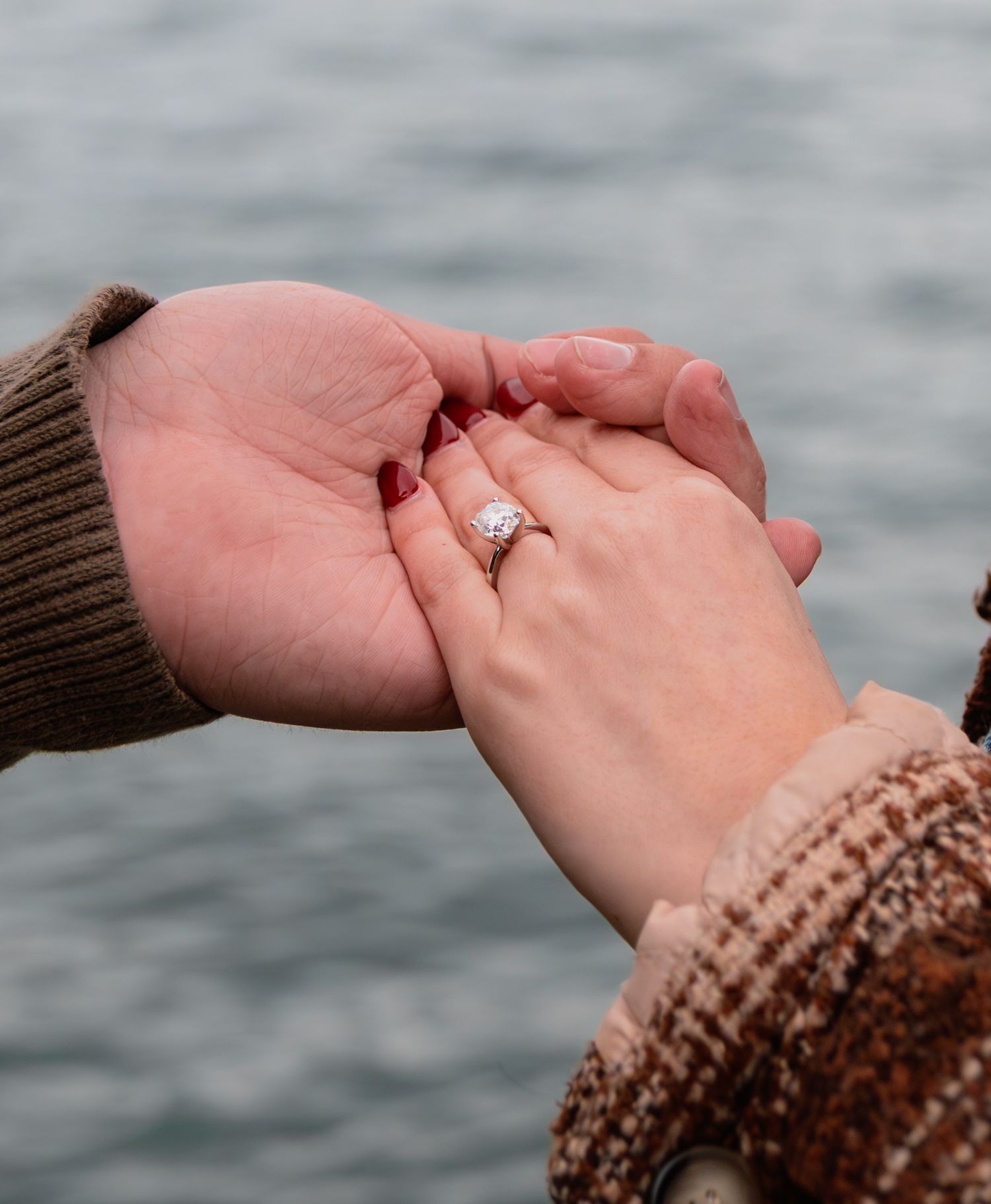 man holding womans hand with diamond ring
