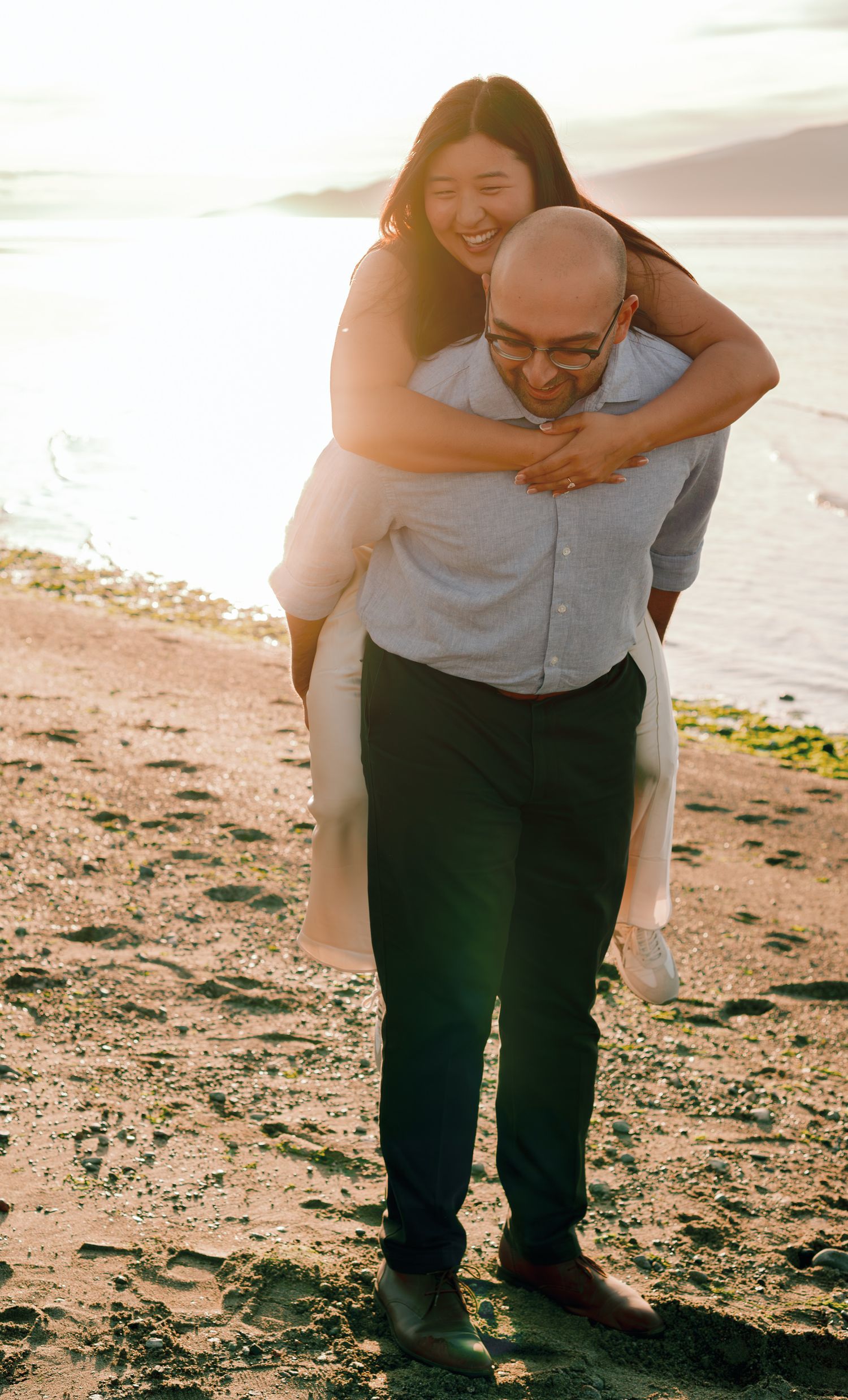 woman on mans back on the beach during golden hour