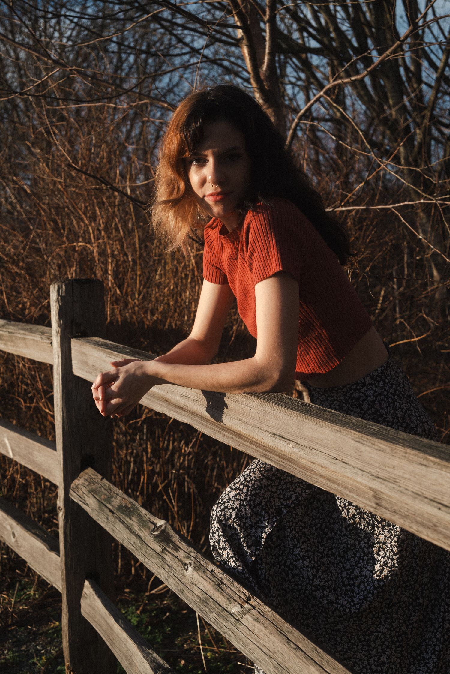 a woman leaning against a fence.