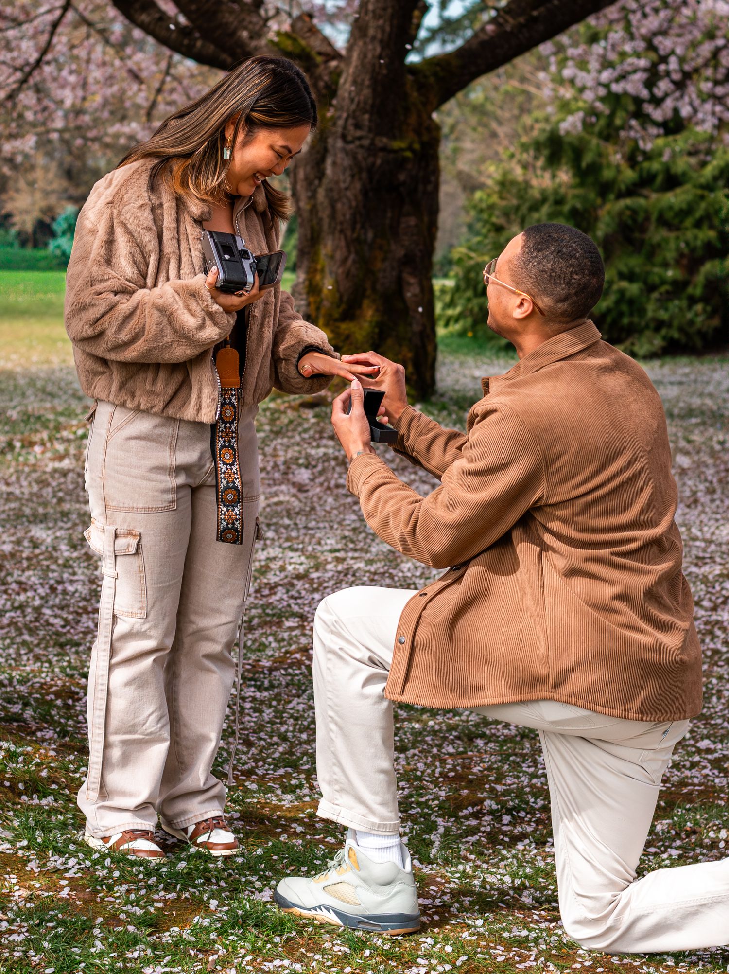 man proposing to woman under cherry blossom trees