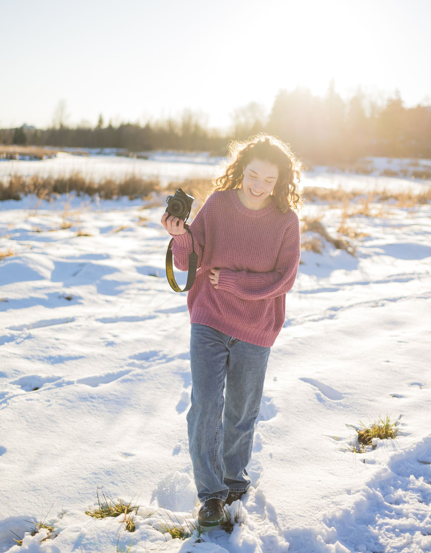 a woman smiling with her camera in the snow