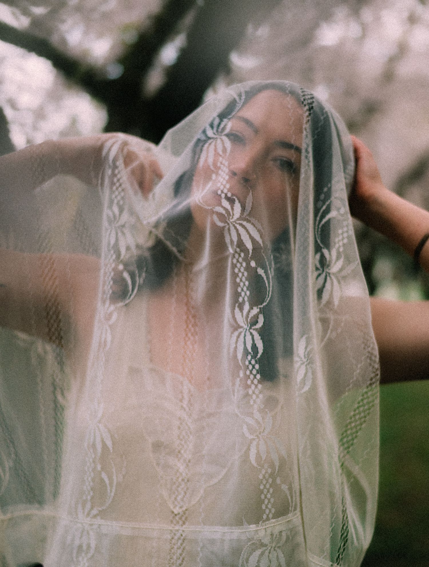 a woman posing with a veil over head.