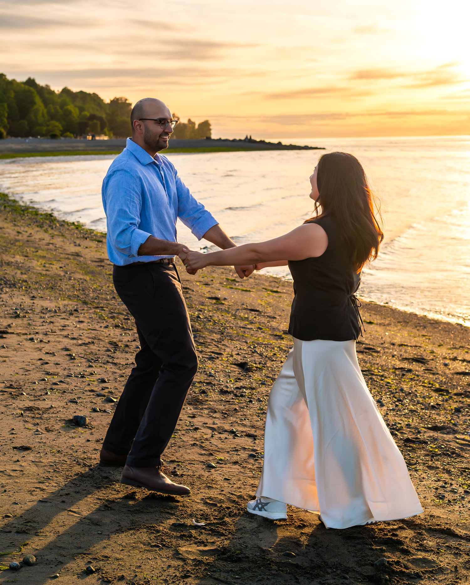 man and woman holding hands and spinning on the beach