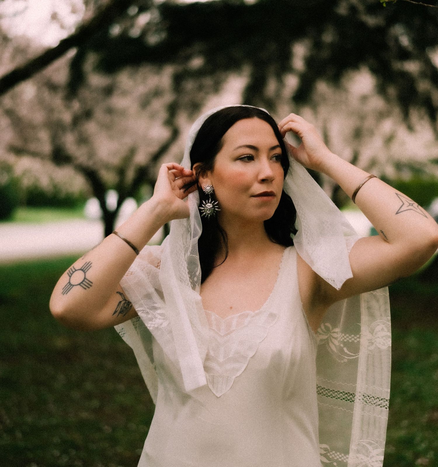 a woman wearing a white dress posing in nature.