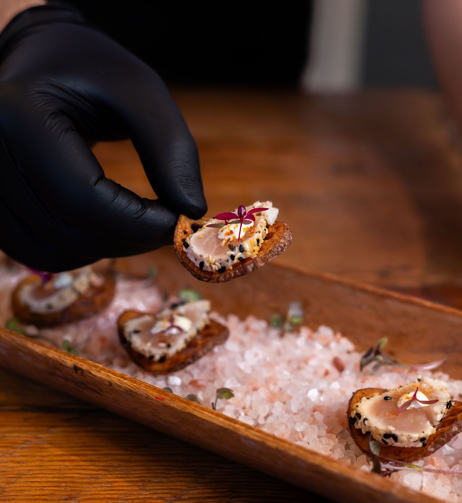 man picking up piece of food with black gloves