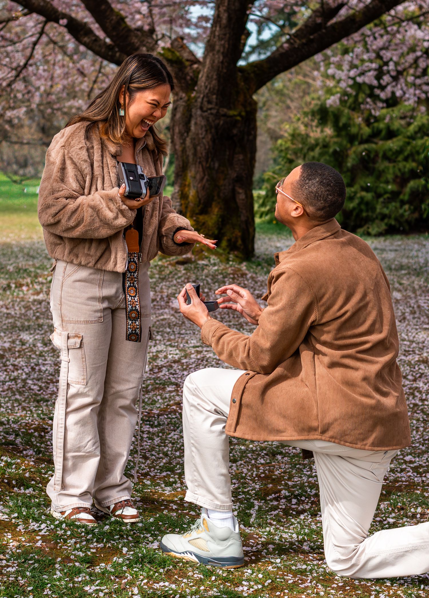 man proposing to woman under cherry blossom trees