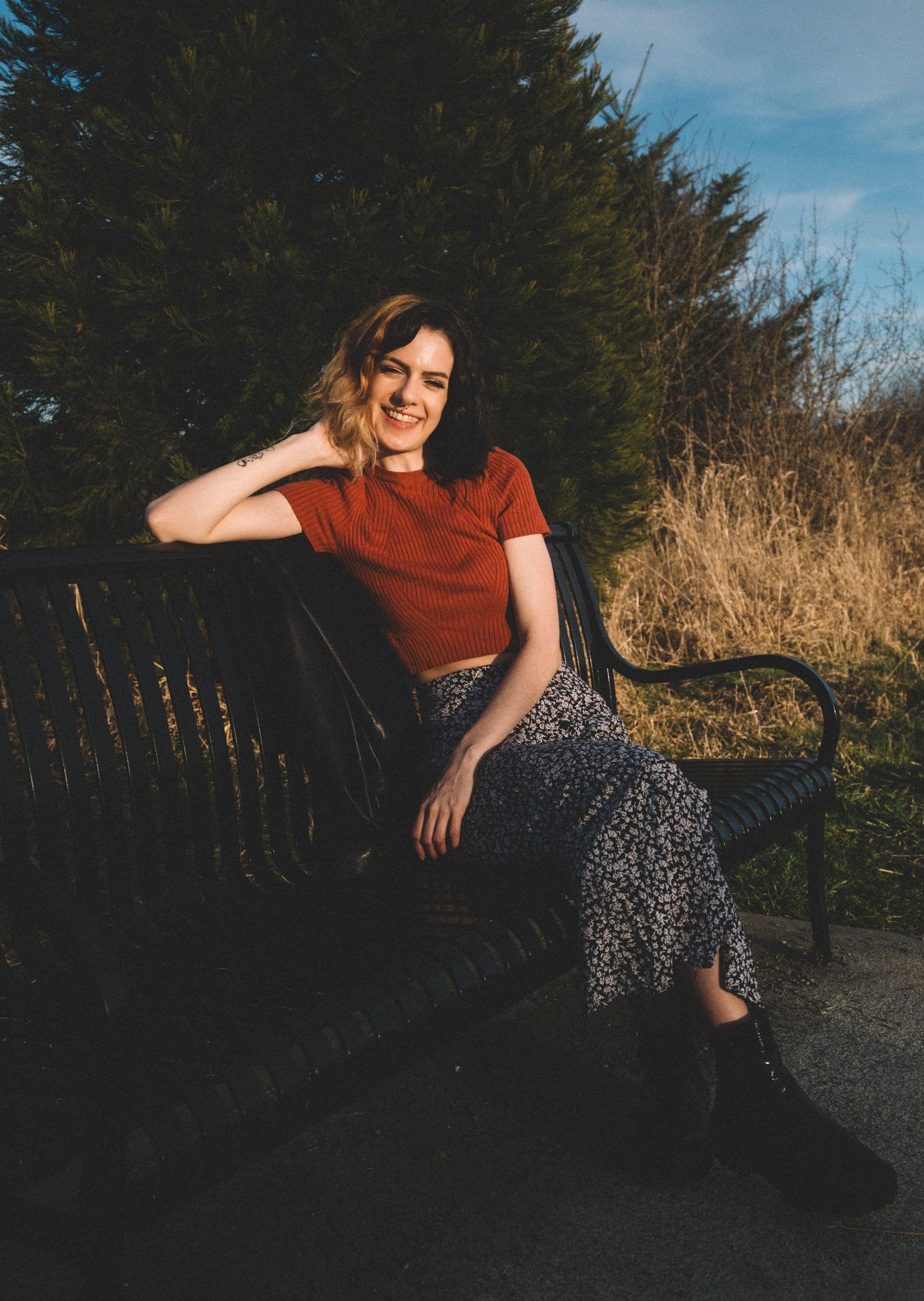 a women sitting on a bench in a natural setting, smiling.