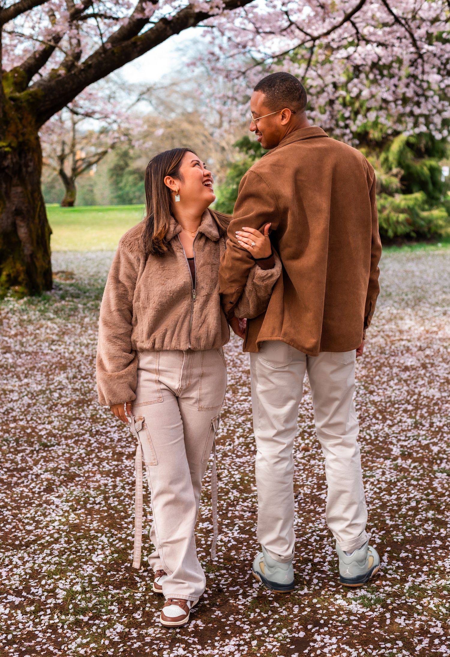 man holding womans arm under cherry blossom trees