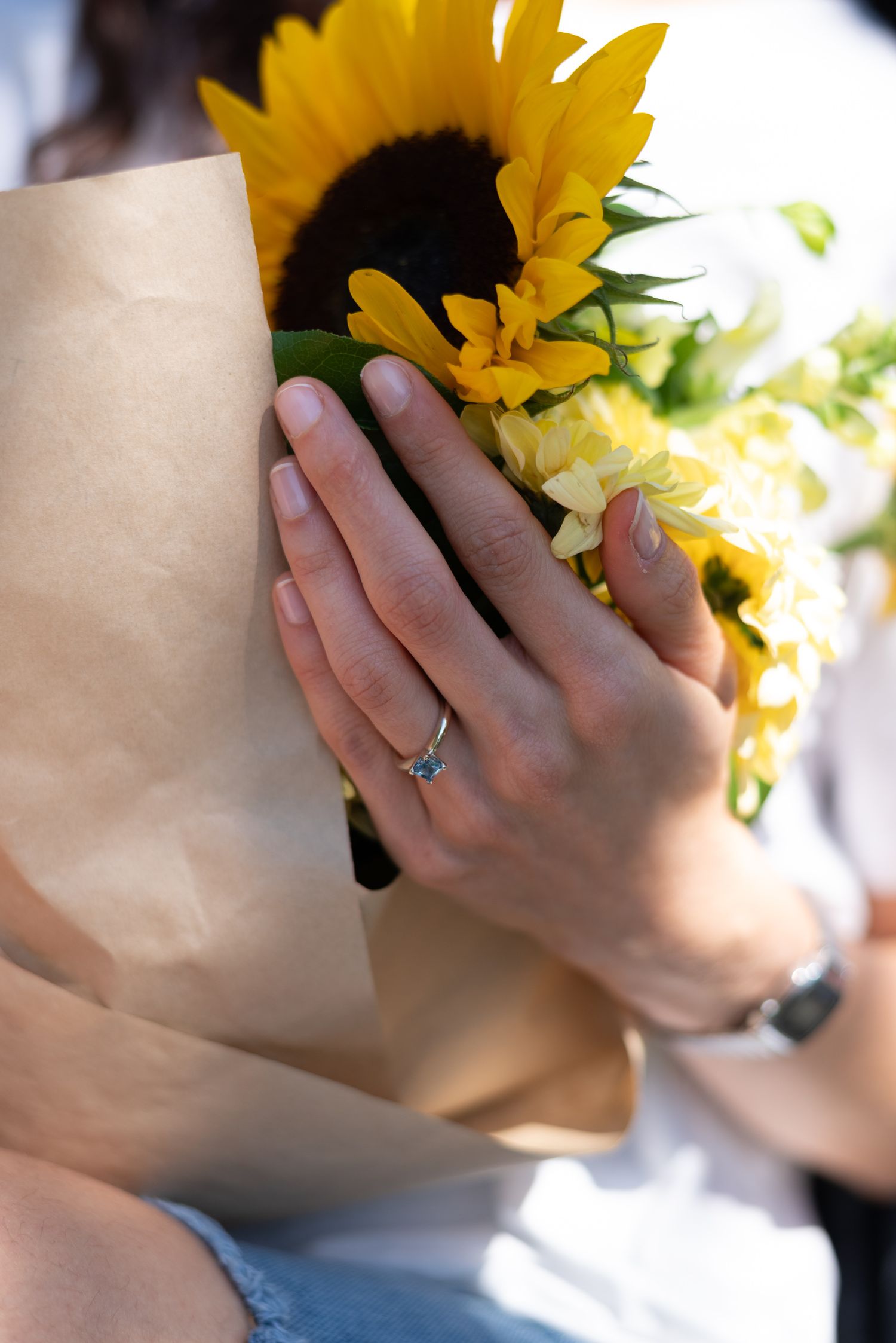 photo of a newly engaged womans hand with ring holding flowers
