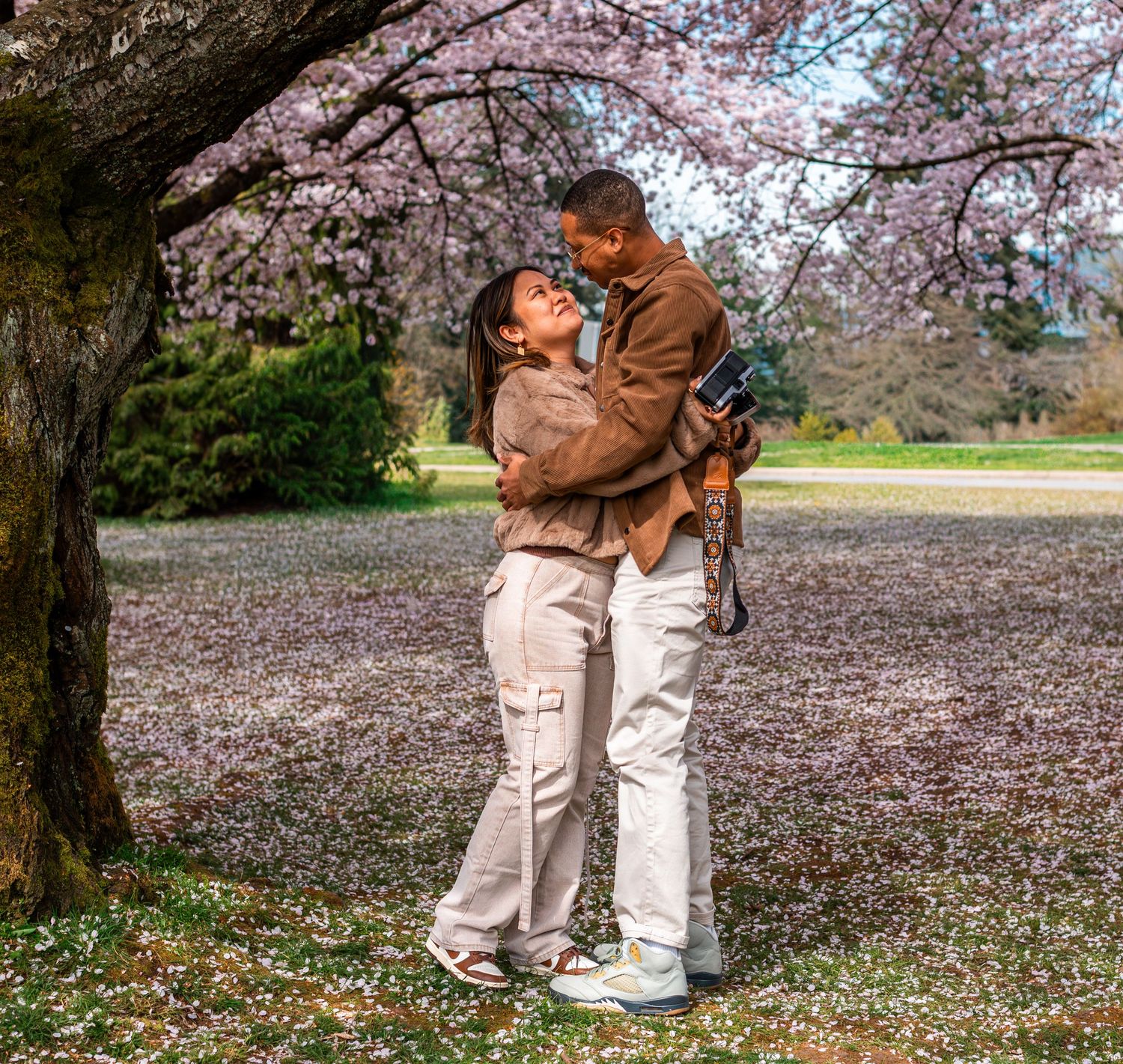 man and woman hugging under cherry blossom trees