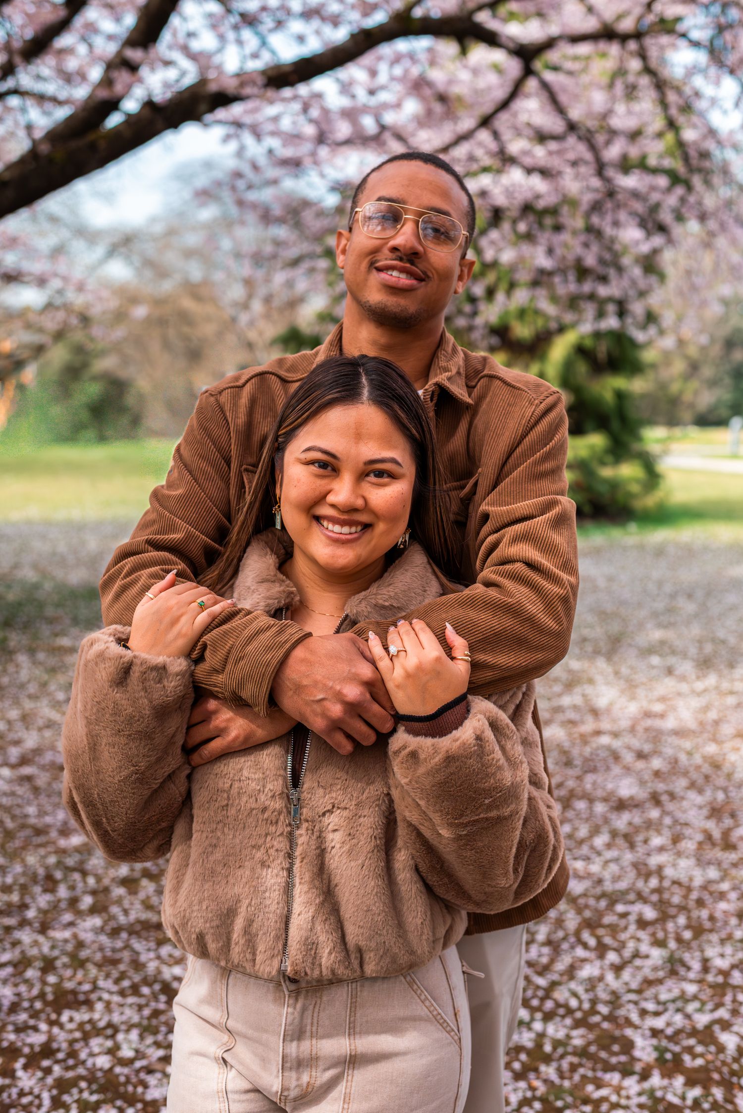 man holding woman and smiling under cherry blossom trees