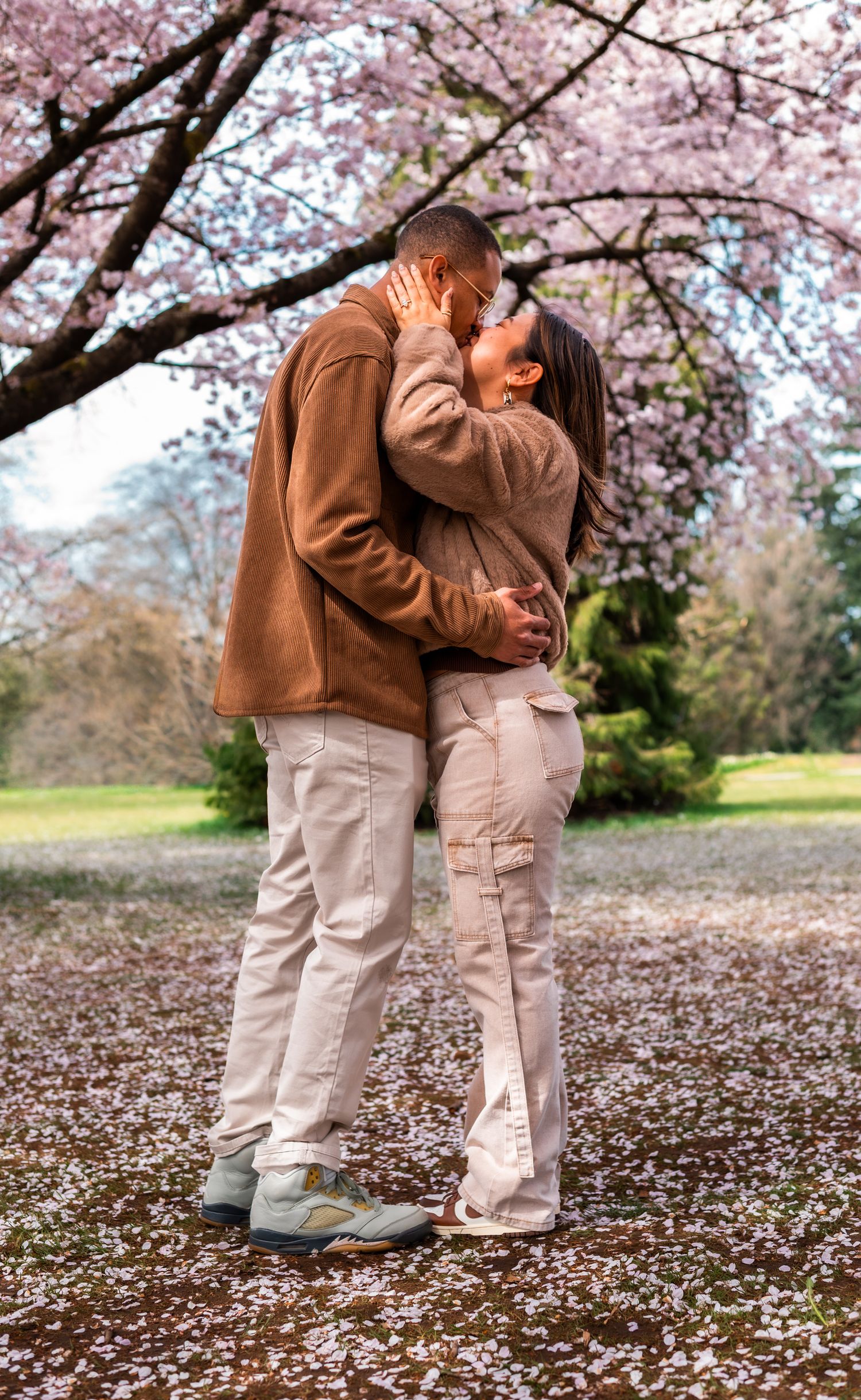 man and woman kissing under cherry blossom trees