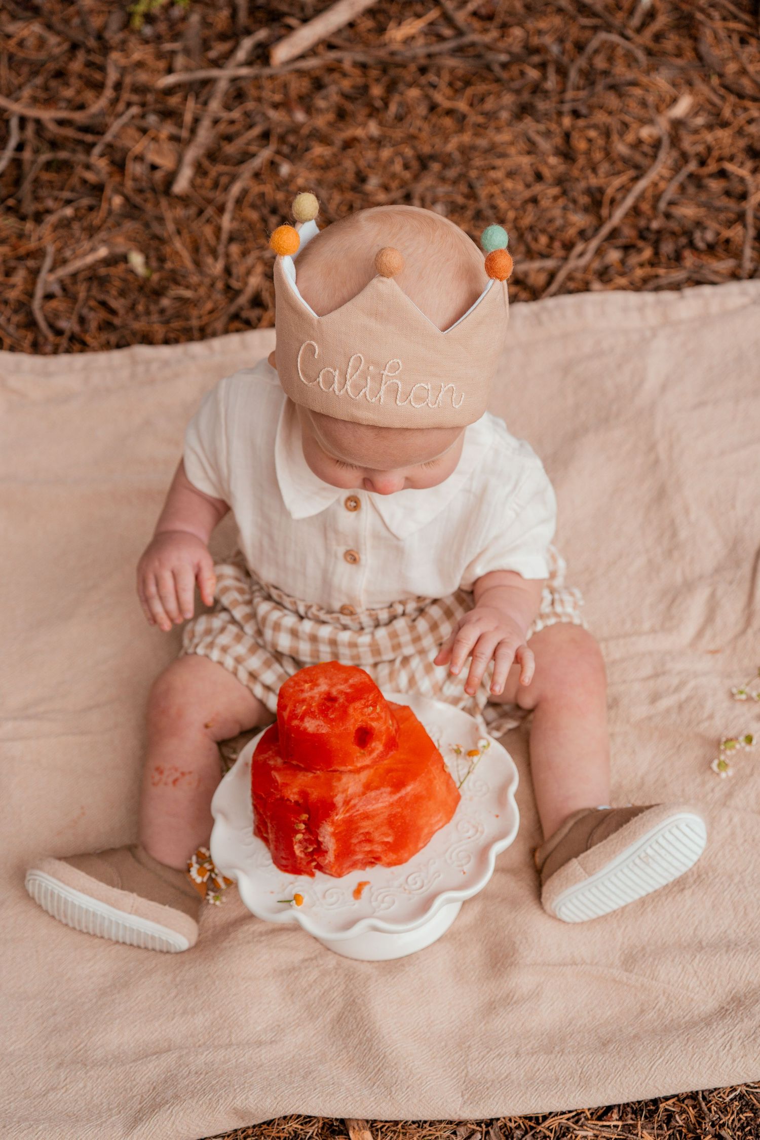A series of photos showing a baby in white shoes sitting with a bright orange pumpkin on a beige blanket.