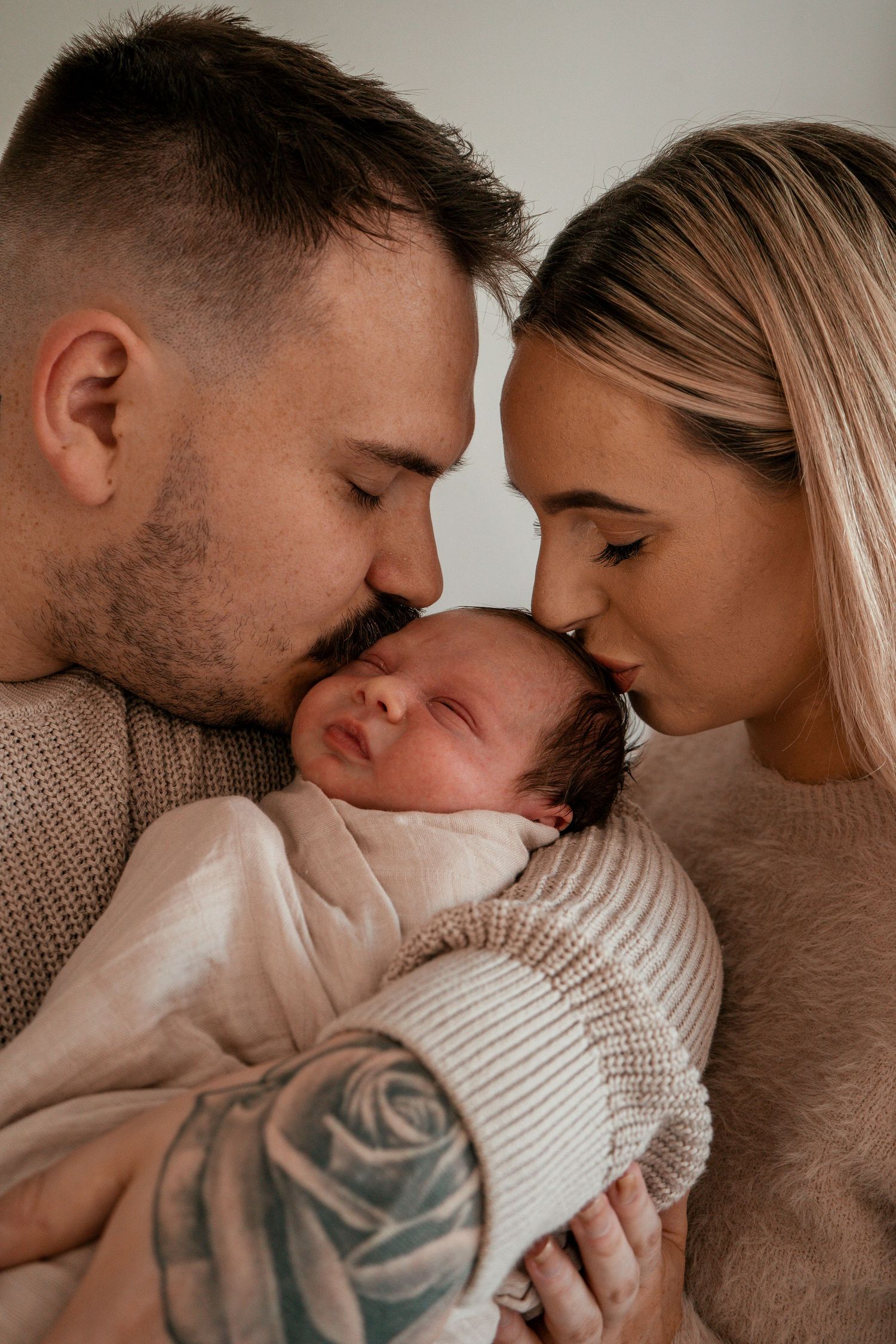 A loving couple shares tender moments with their newborn baby in a series of intimate family portraits.