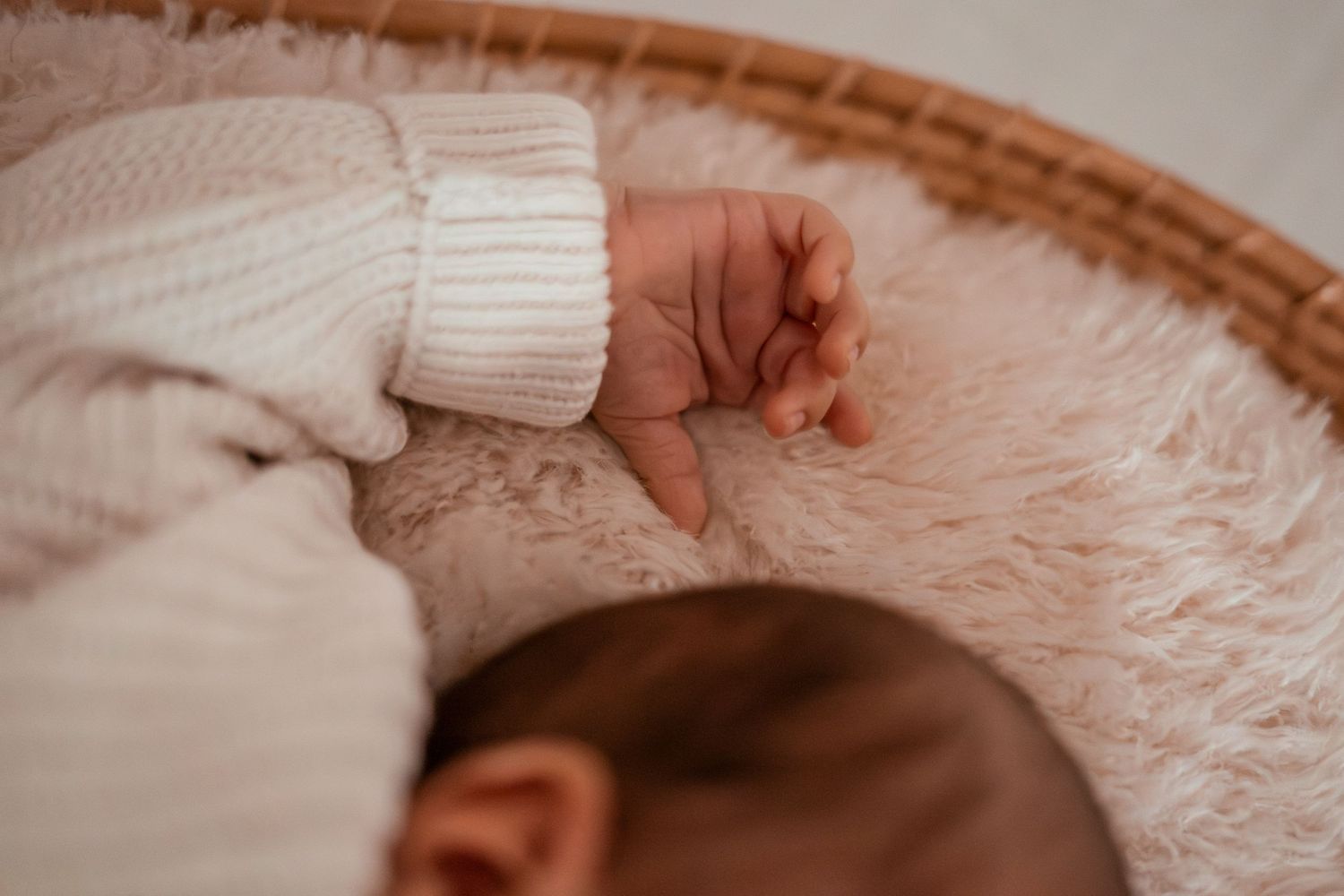 A close-up view of a person's hand gently touching soft pink fabric in a delicate and intimate manner.